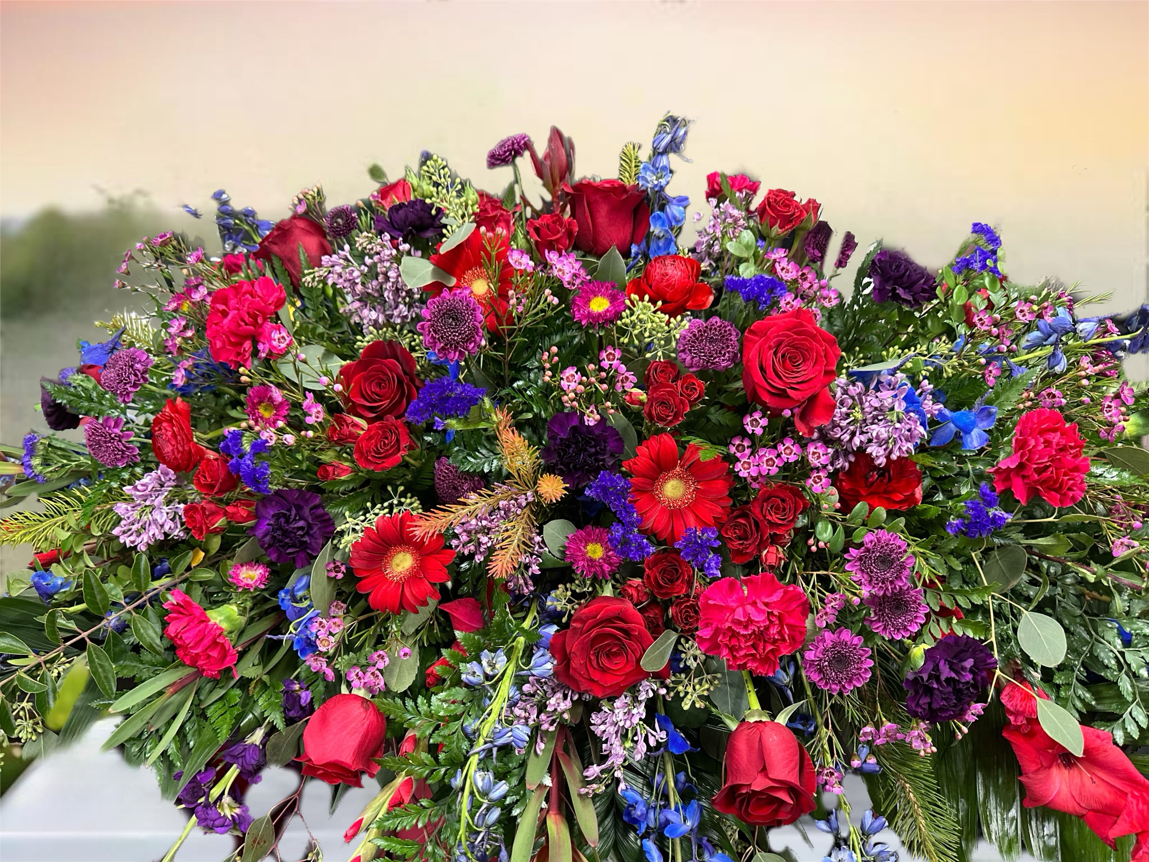 Large mixed floral spray with red roses, purple blooms, and blue flowers
