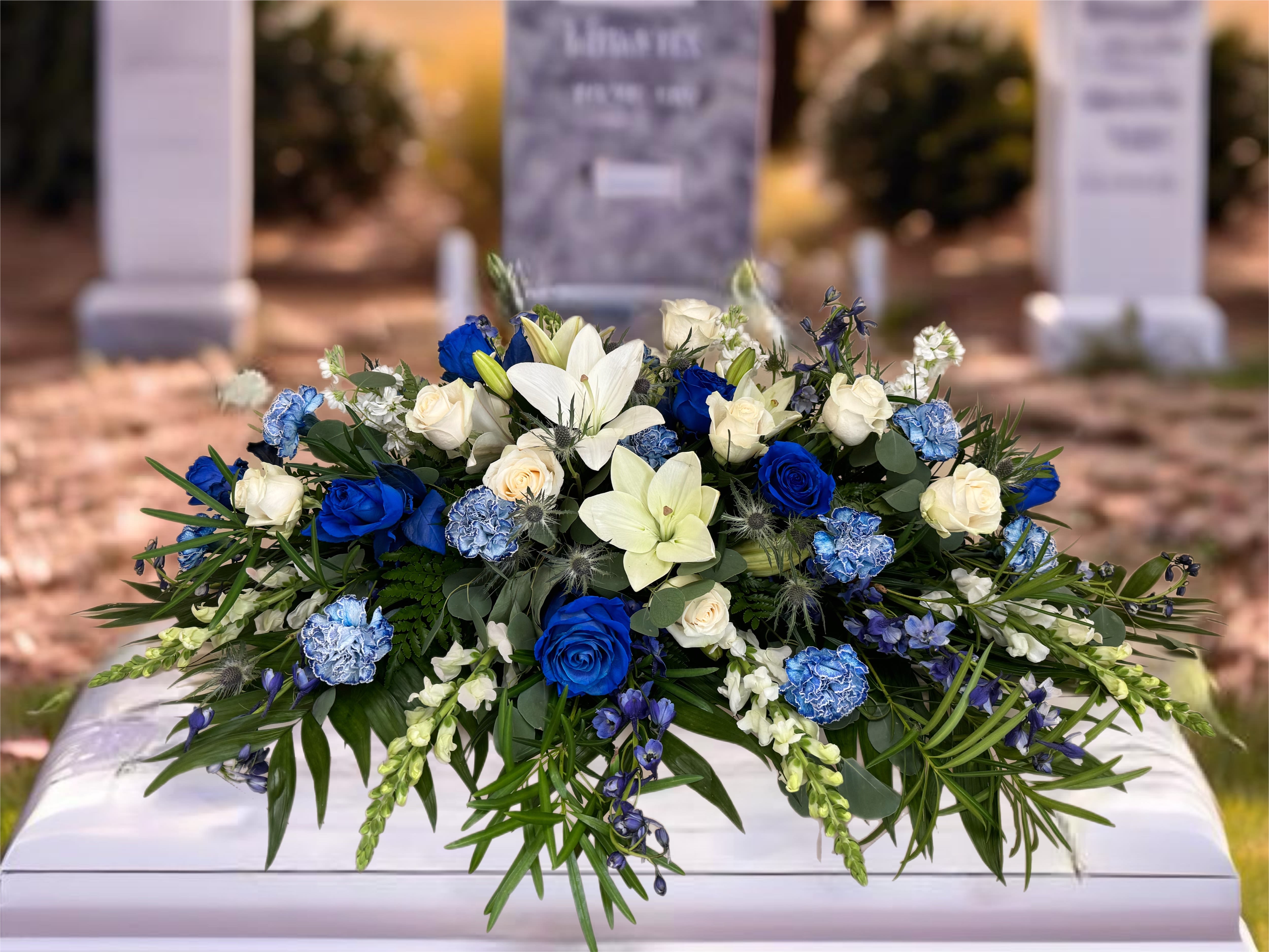Blue and white floral casket spray with roses and lilies