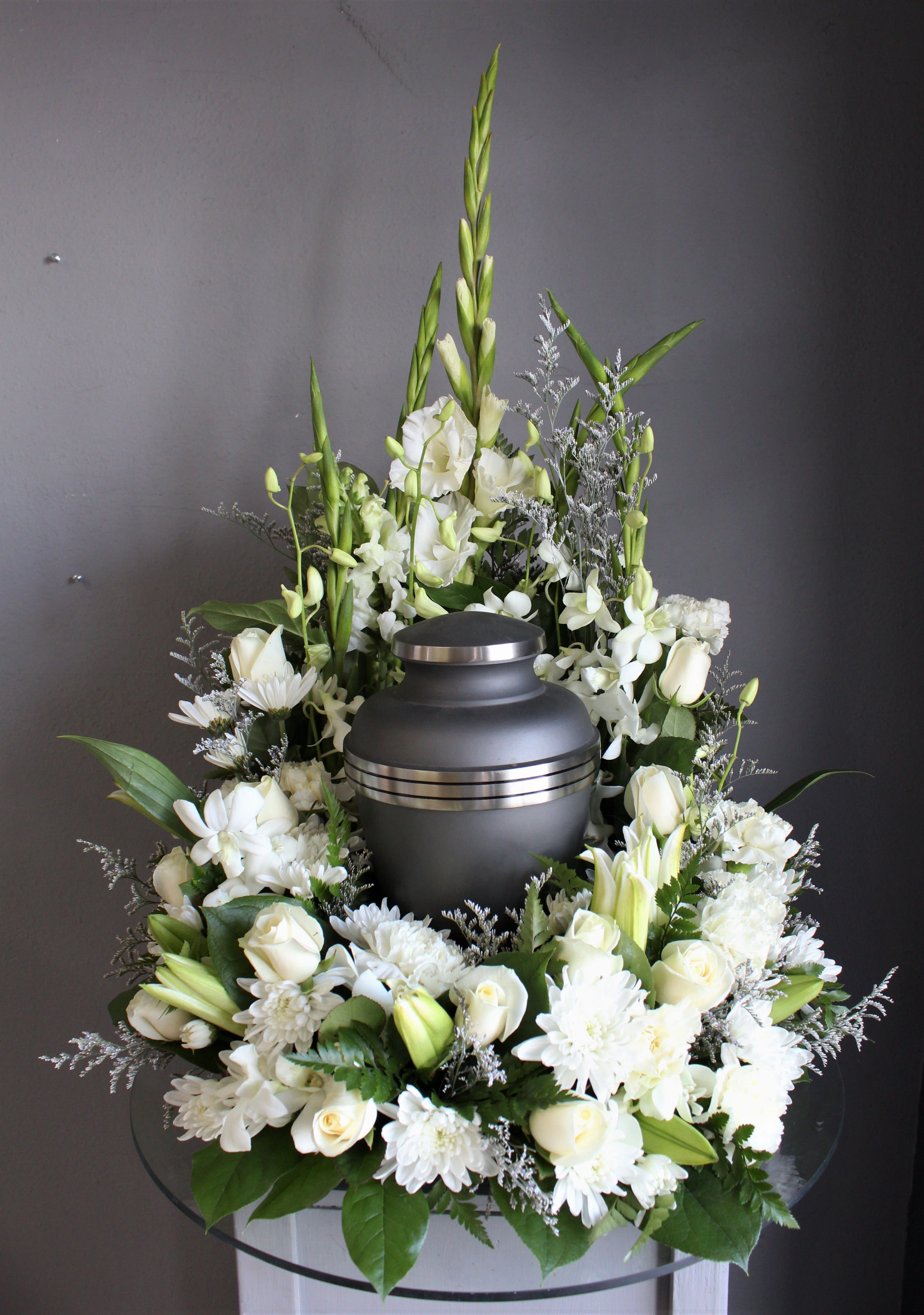 White floral funeral urn arrangement with roses, lilies, and chrysanthemums