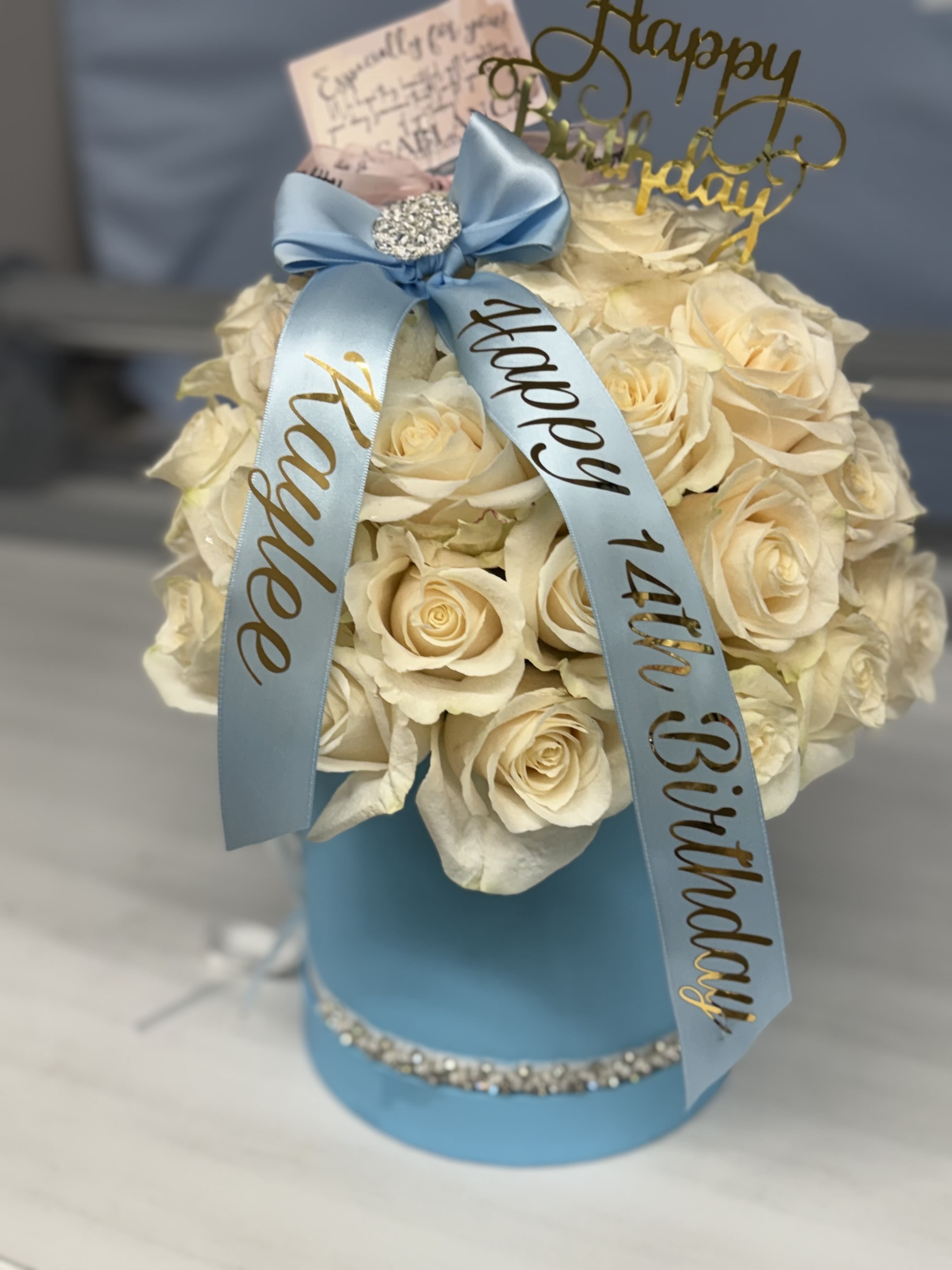 Cream rose arrangement in a blue hat box with a birthday ribbon