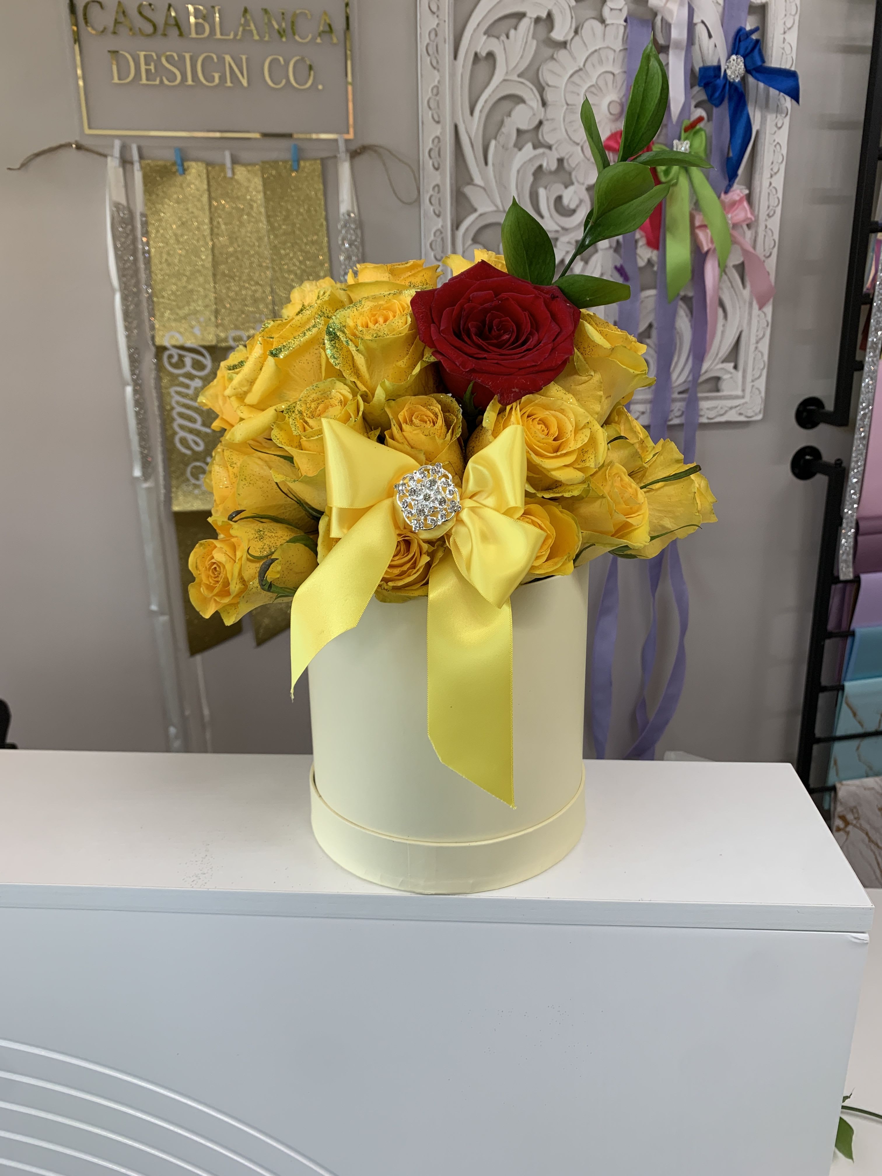 Yellow and red rose arrangement in a cream hat box with a yellow bow
