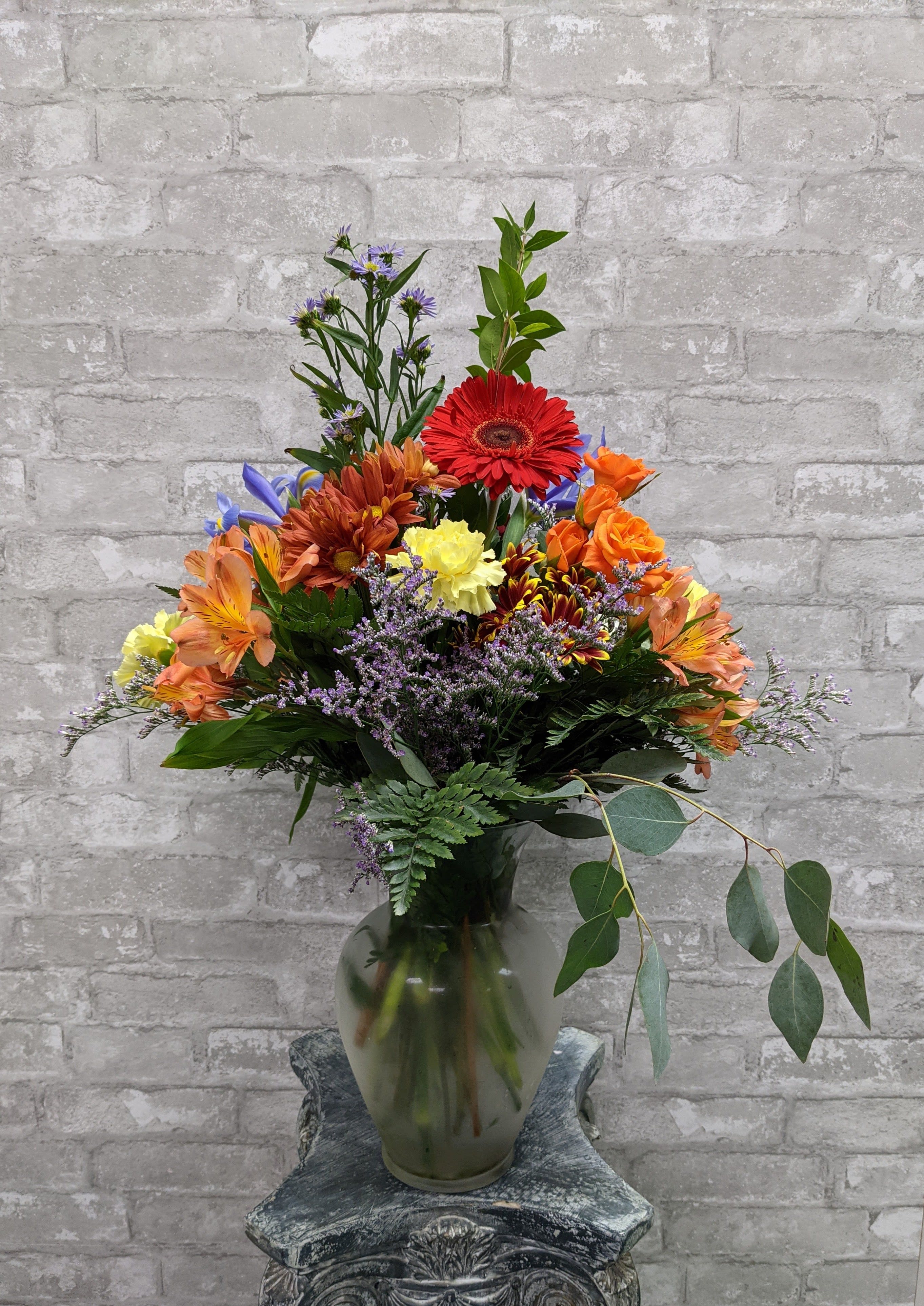 Mixed bouquet in a glass vase with red, orange, yellow, and purple flowers