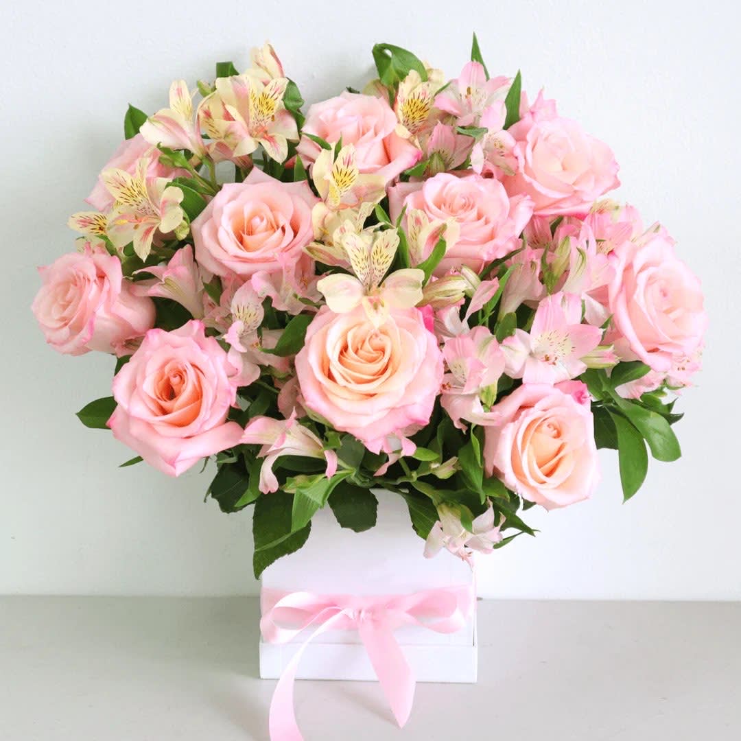 Pink roses and pale alstroemeria in a white box tied with a pink ribbon