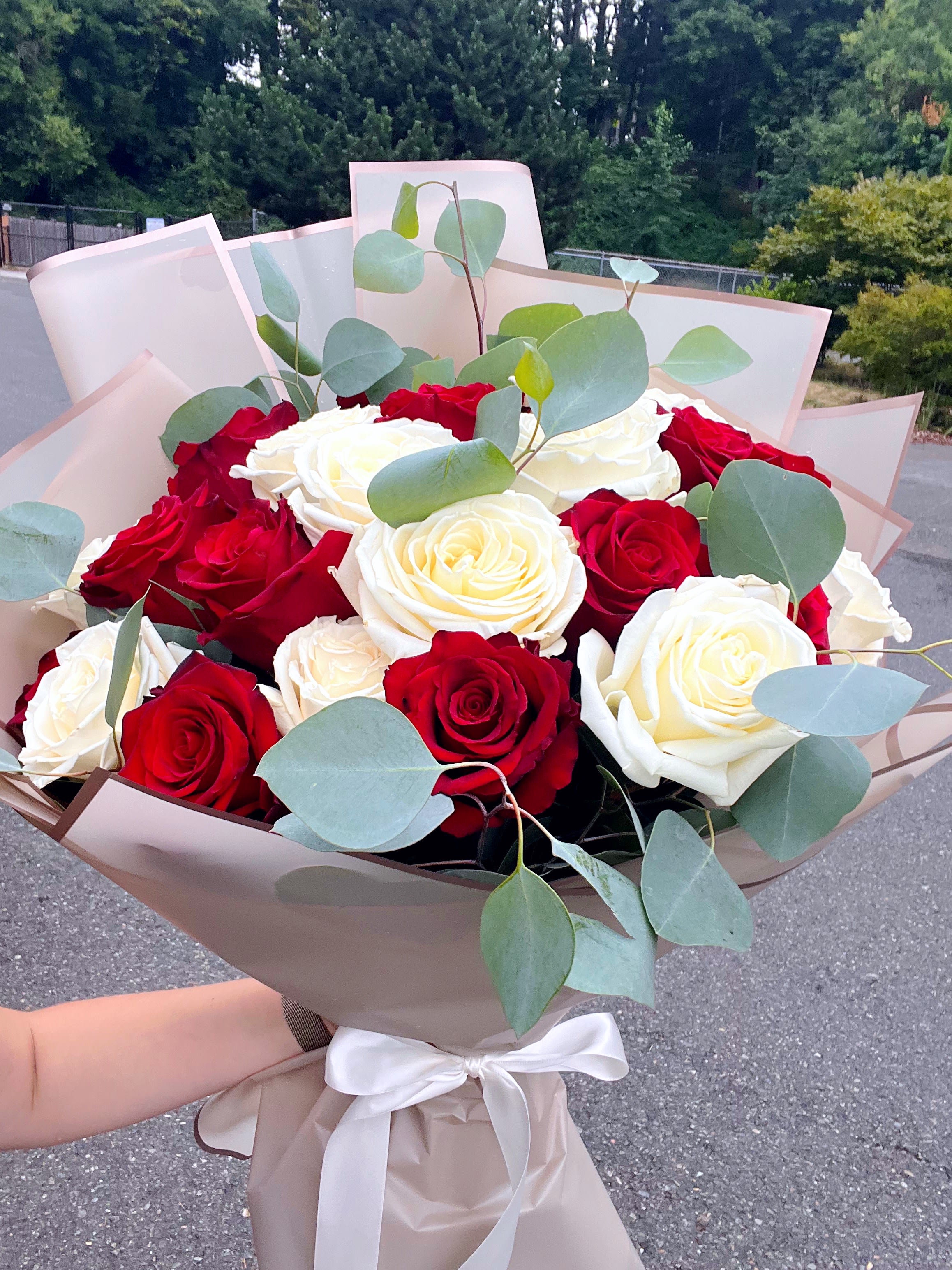 Bouquet of red and white roses with eucalyptus in beige wrap
