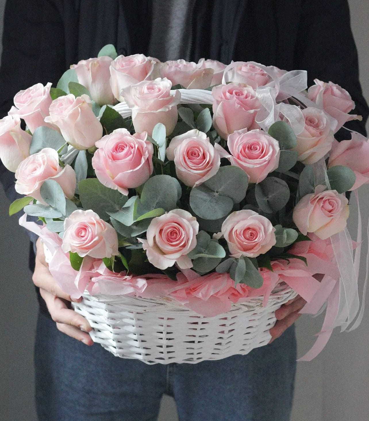 Pink roses arranged in a white basket with ribbon