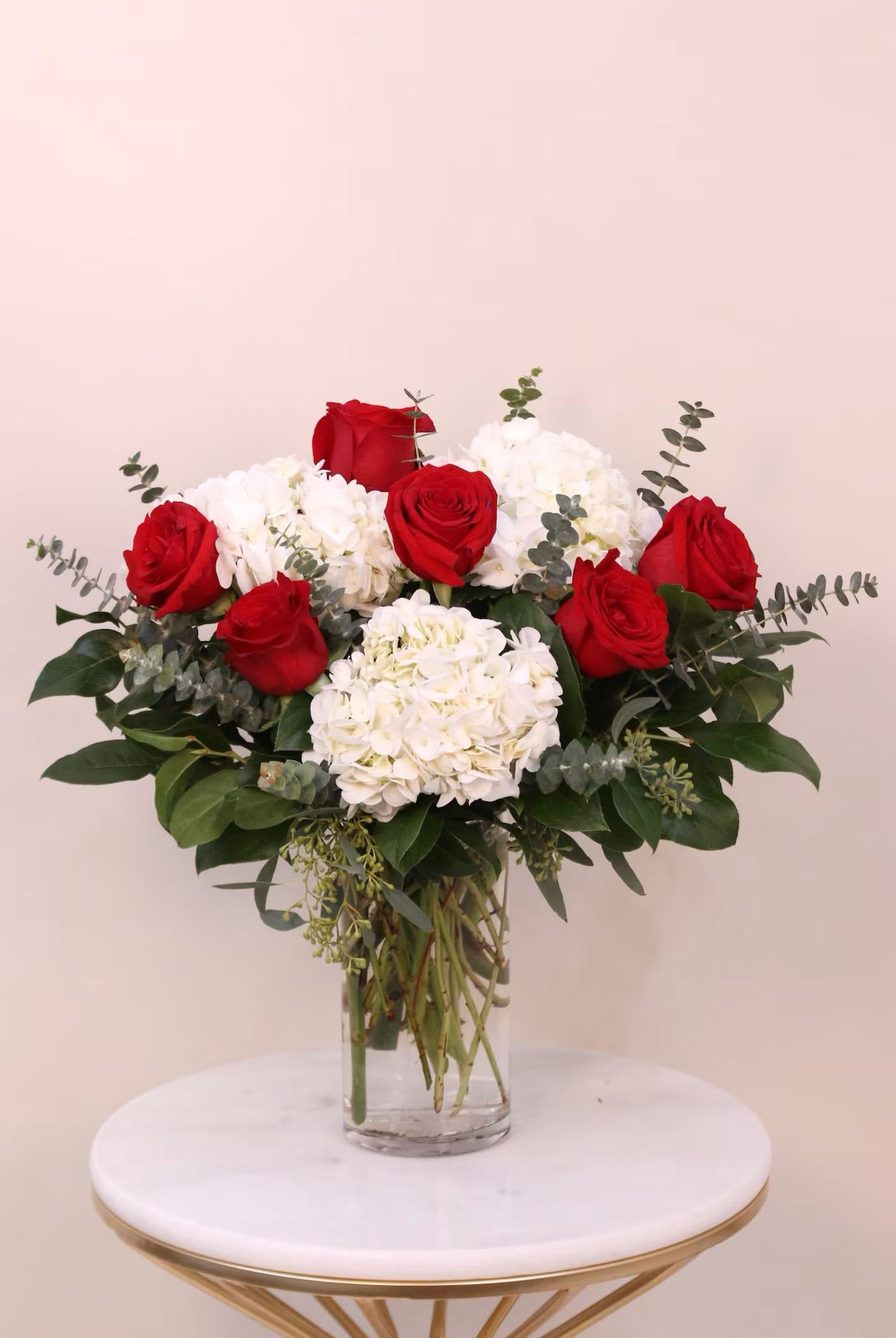 Red roses and white hydrangeas in a clear glass vase