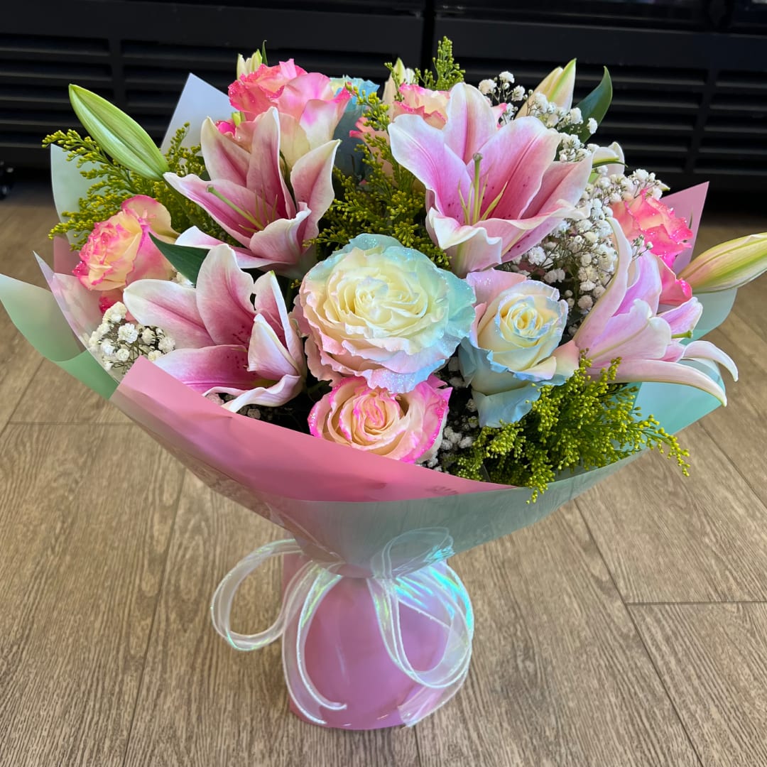 Pink lilies and pastel roses in a wrapped bouquet with a pink vase