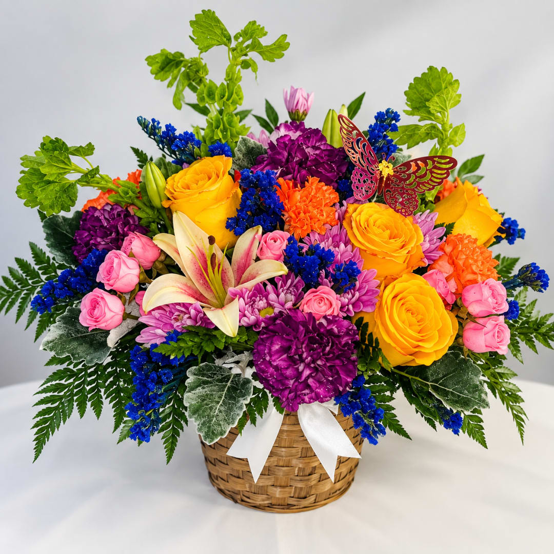 Colorful mixed flower arrangement in a woven basket with a white ribbon