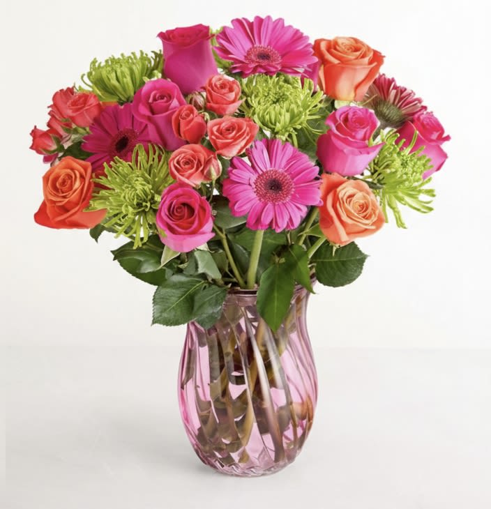 Mixed pink and orange flowers in a pink glass vase