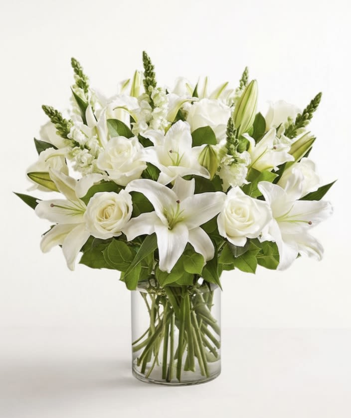 White lilies and roses arranged in a clear glass vase