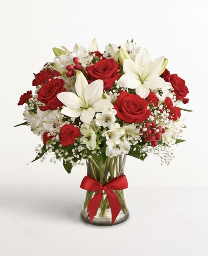 Red roses and white lilies in a glass vase with a red ribbon