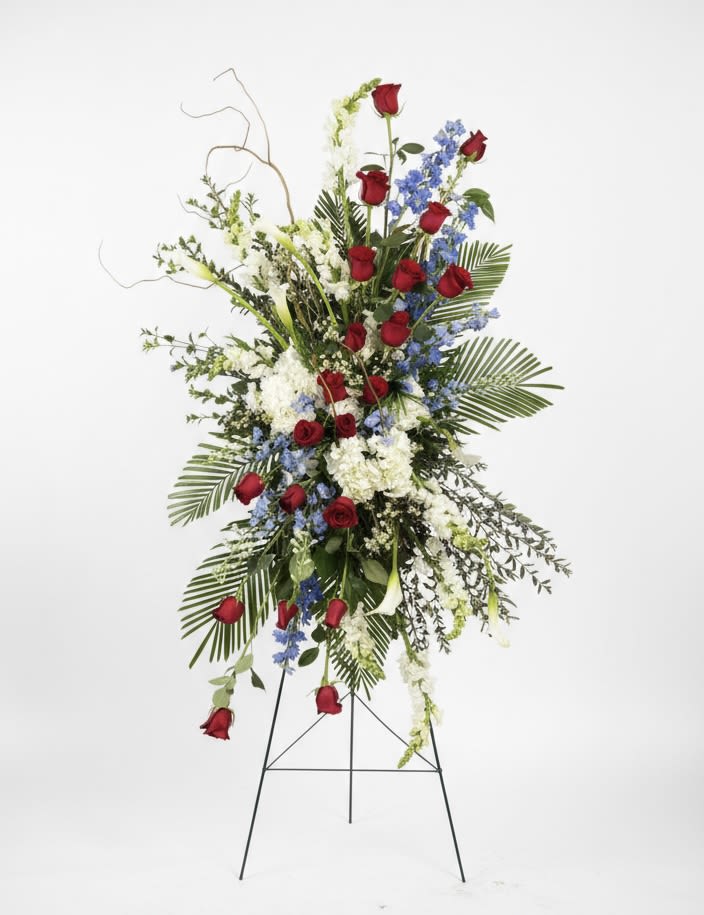 Tall standing floral spray with red roses, white blooms, and blue flowers