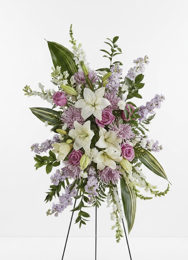 Standing floral spray with white lilies and pink roses on a black easel