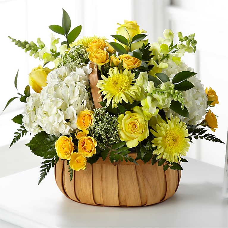 Yellow and white flower arrangement in a woven basket