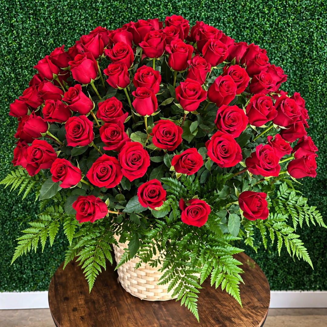 Large bouquet of red roses in a woven basket with fern foliage