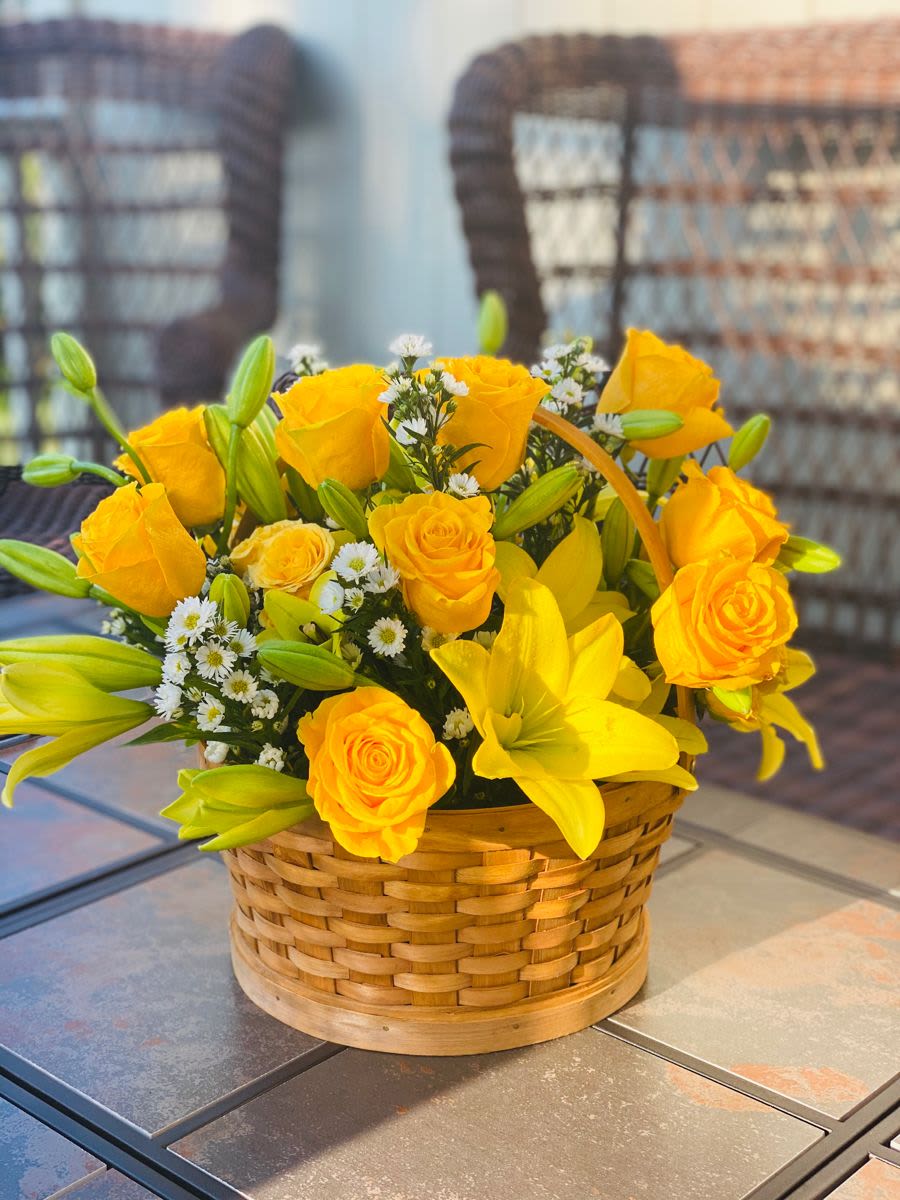 Ilusión Dorada - A bright and uplifting arrangement designed in a natural basket, featuring open yellow lilies and fresh yellow roses. The blend of textures and golden tones creates a warm, cheerful, and elegant design—perfect for brightening any space, celebrating a milestone, or sending joy and positive energy.