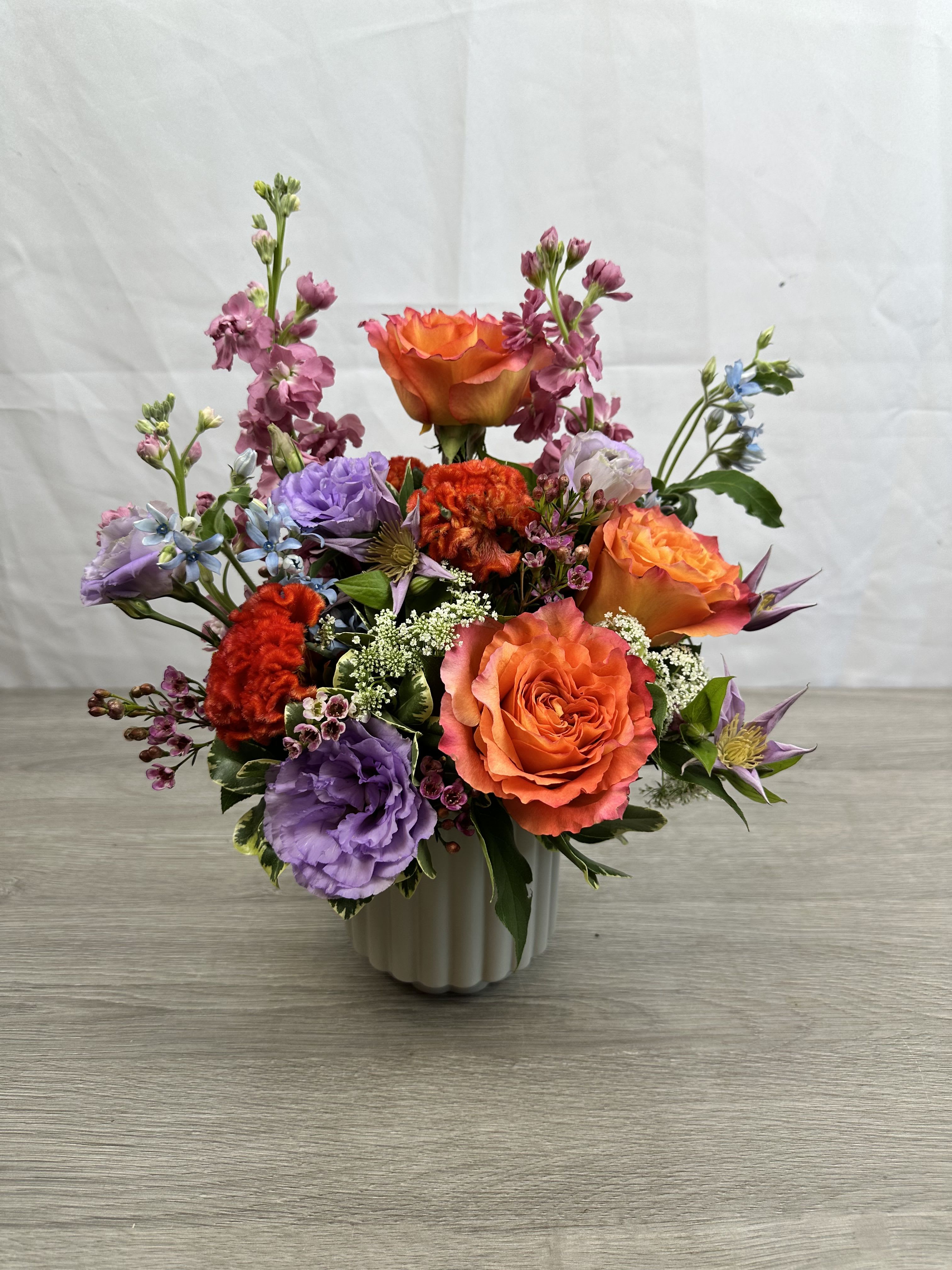 Tuscan Twilight - A bold burst of orange roses framed by purple and pink blooms-Tuscan Twilight is the kind of birthday bouquet or anniversary arrangement that makes the person you're thinking of stop, smile, and linger. 
