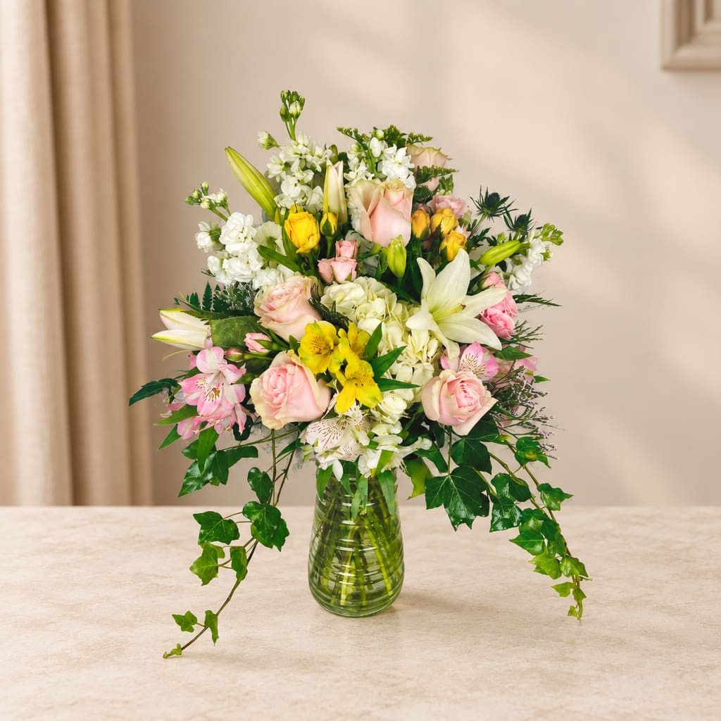 Mixed bouquet of lilies, roses, and white blooms in a glass vase