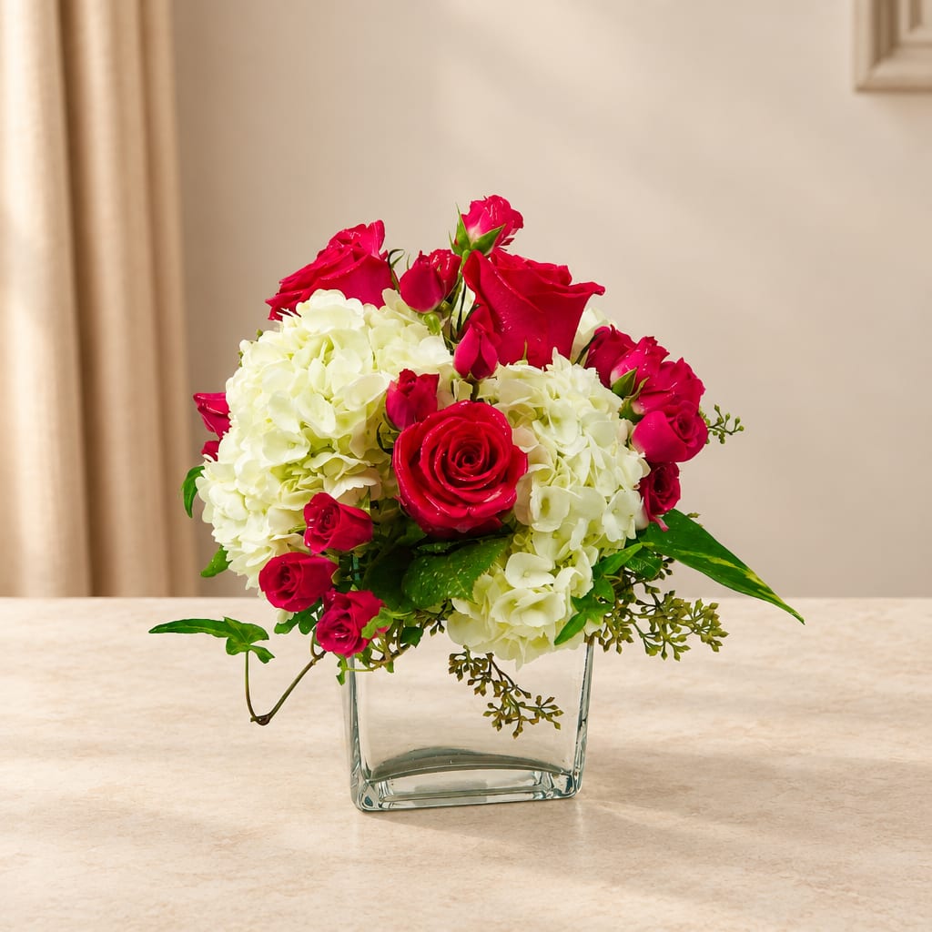 Pink roses and white hydrangeas arranged in a clear glass vase