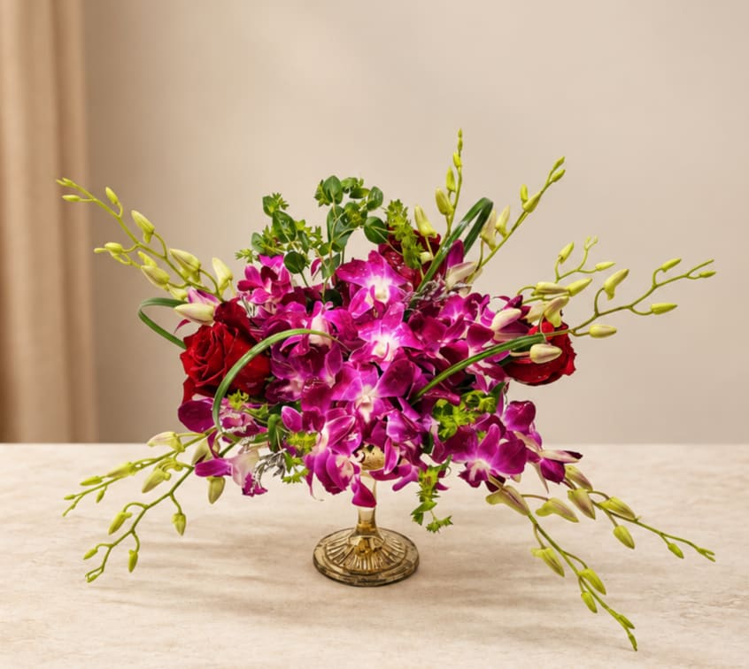 Pink orchids and red roses arranged in a gold vase
