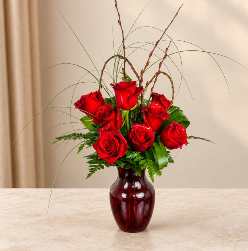 Red roses arranged in a burgundy glass vase
