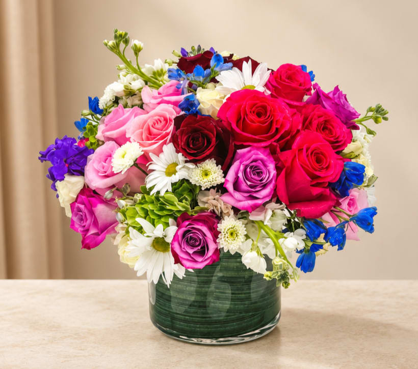 Mixed bouquet of roses and daisies in a green glass vase