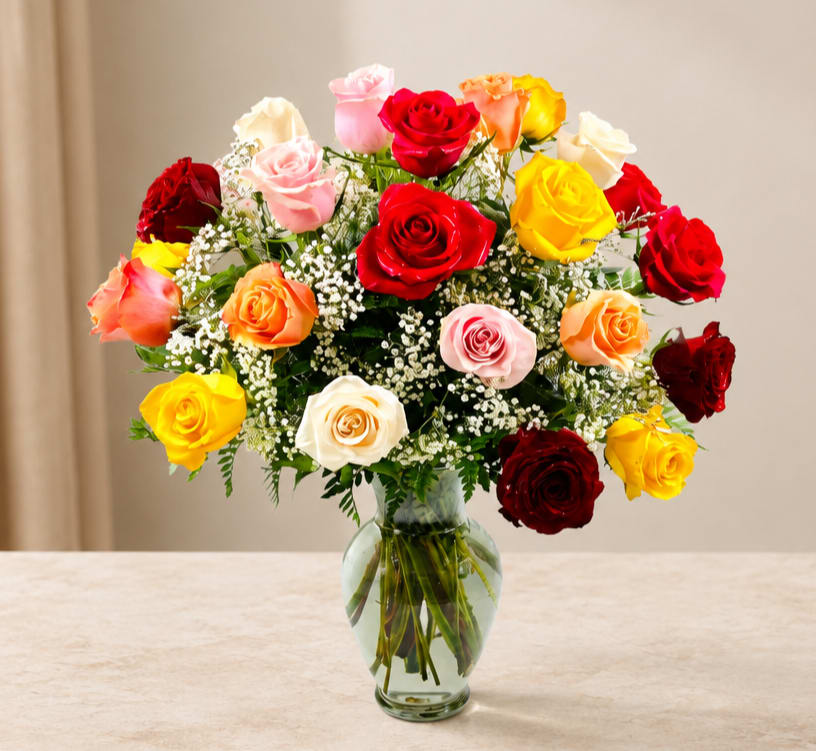Mixed roses in red, pink, yellow, peach, and white in a clear glass vase
