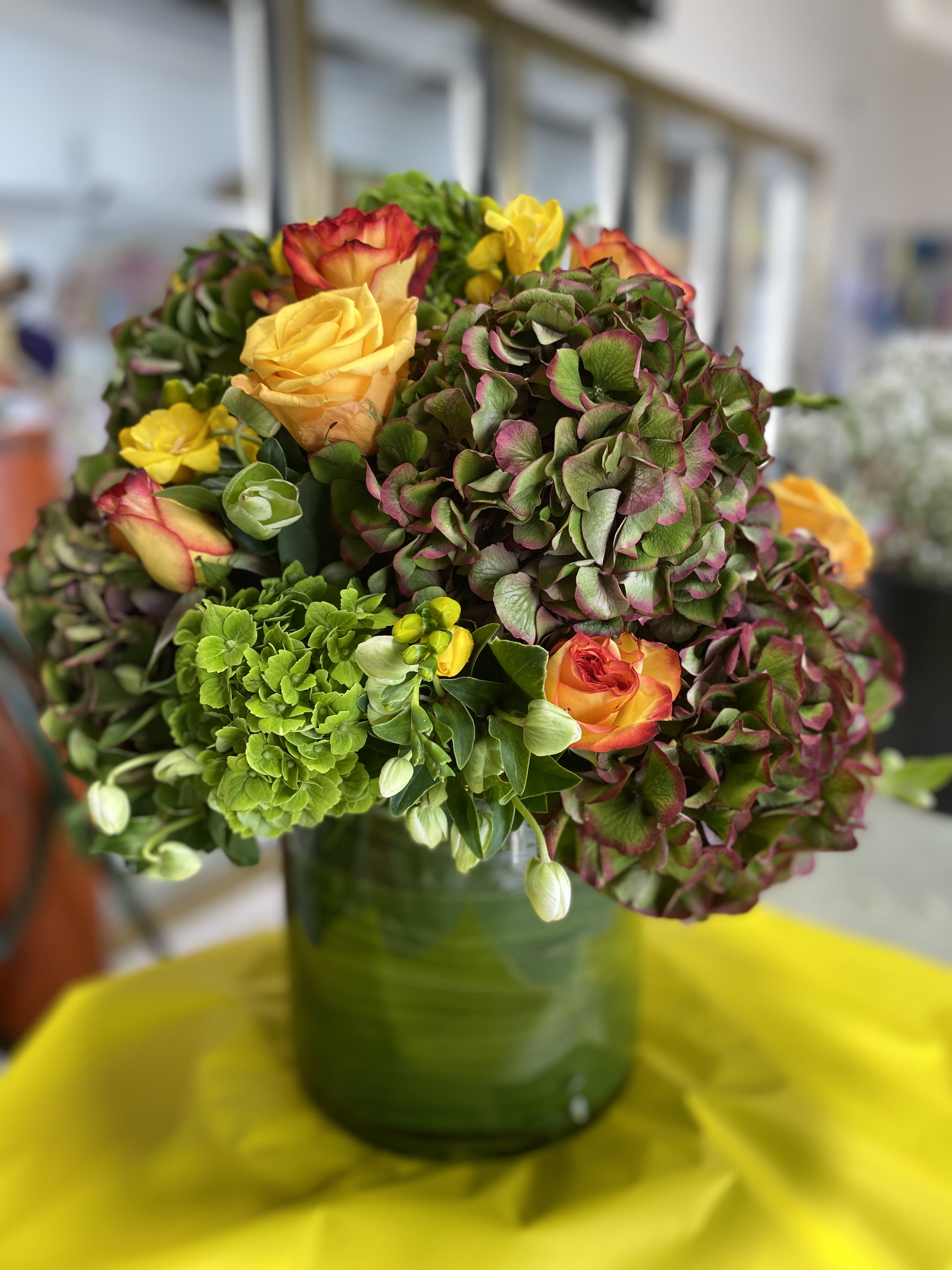 Dutch Splendor - Mixture of Fall &amp; Winter- Color Dutch Hydrangea - Fall color Roses - Mini Green Hydrangea and Yellow Freesia  , accented with Helleborus  - Arranged in a Tall 10 or 12 inch Glass Cylinder Vase and carefully wrapped inside with a Leaf - Standing in total about 18-20 inches tall and about 14 inches wide.