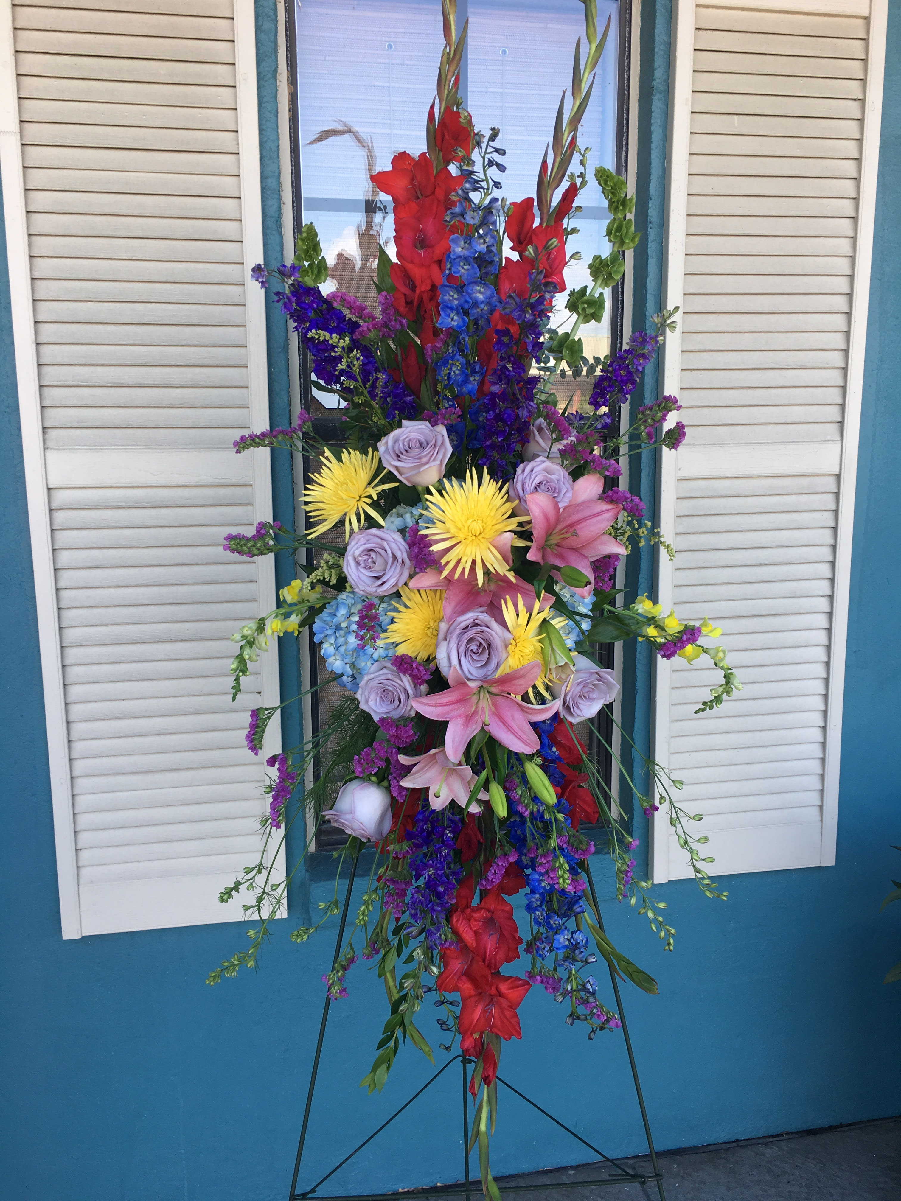 Tall standing floral spray with red, blue, purple, pink, and yellow blooms