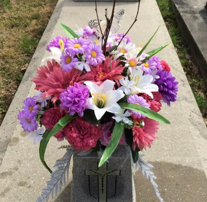 Colorful floral arrangement with daisies, lilies, and pink blooms in a cemetery vase