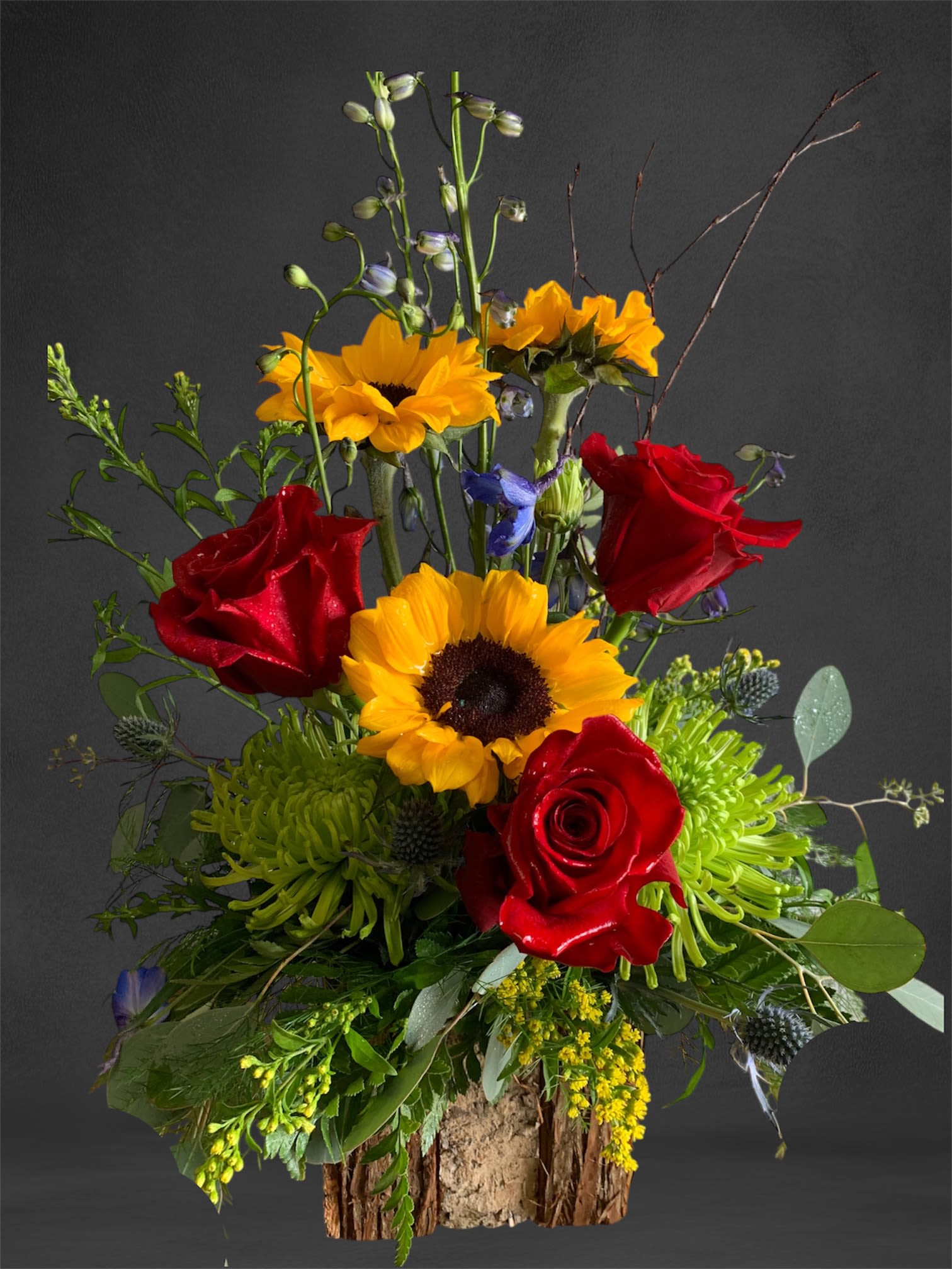 Tall bouquet with red roses and yellow sunflowers in a rustic wood base