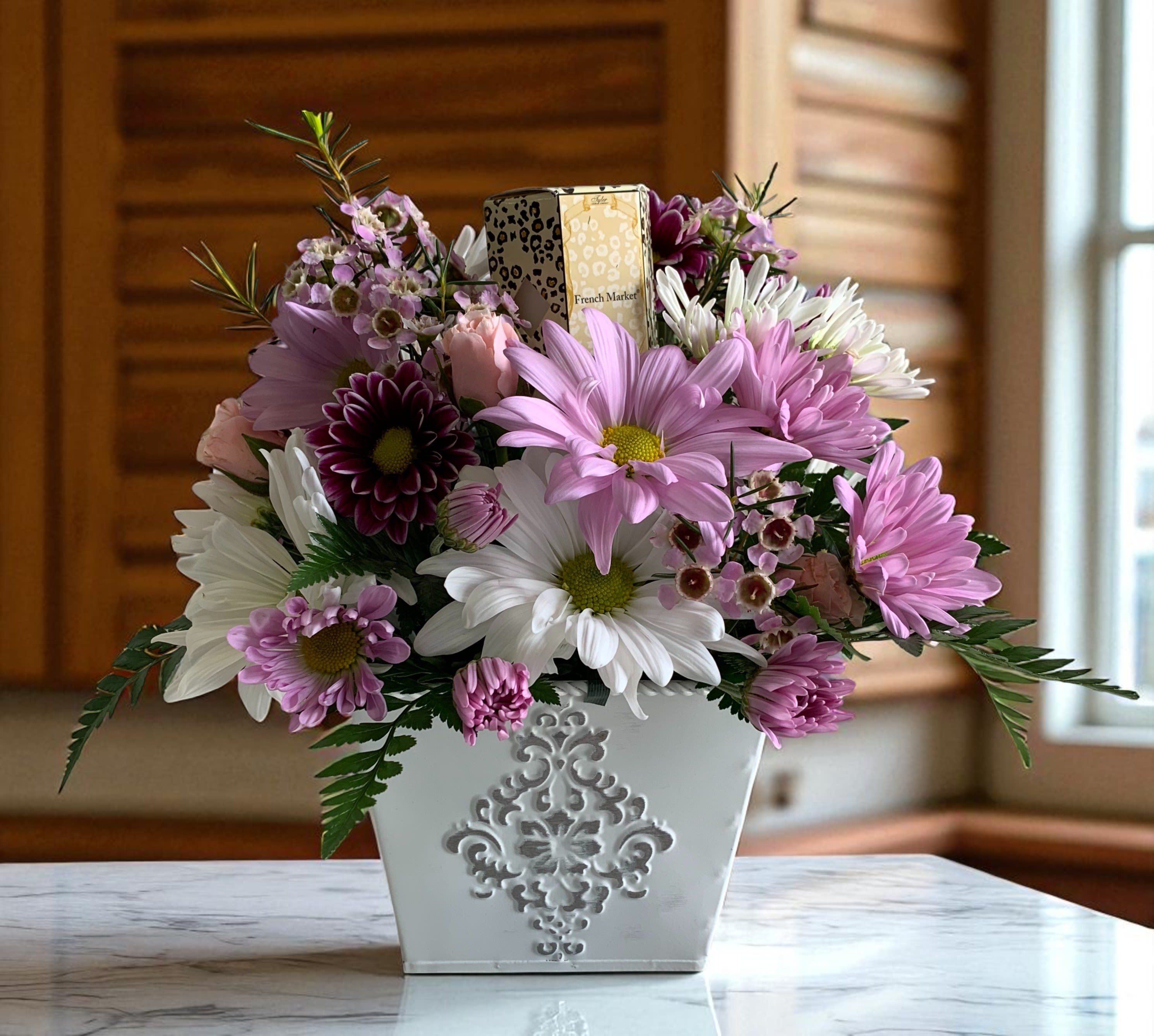 Pink and white daisy bouquet in a white decorative container