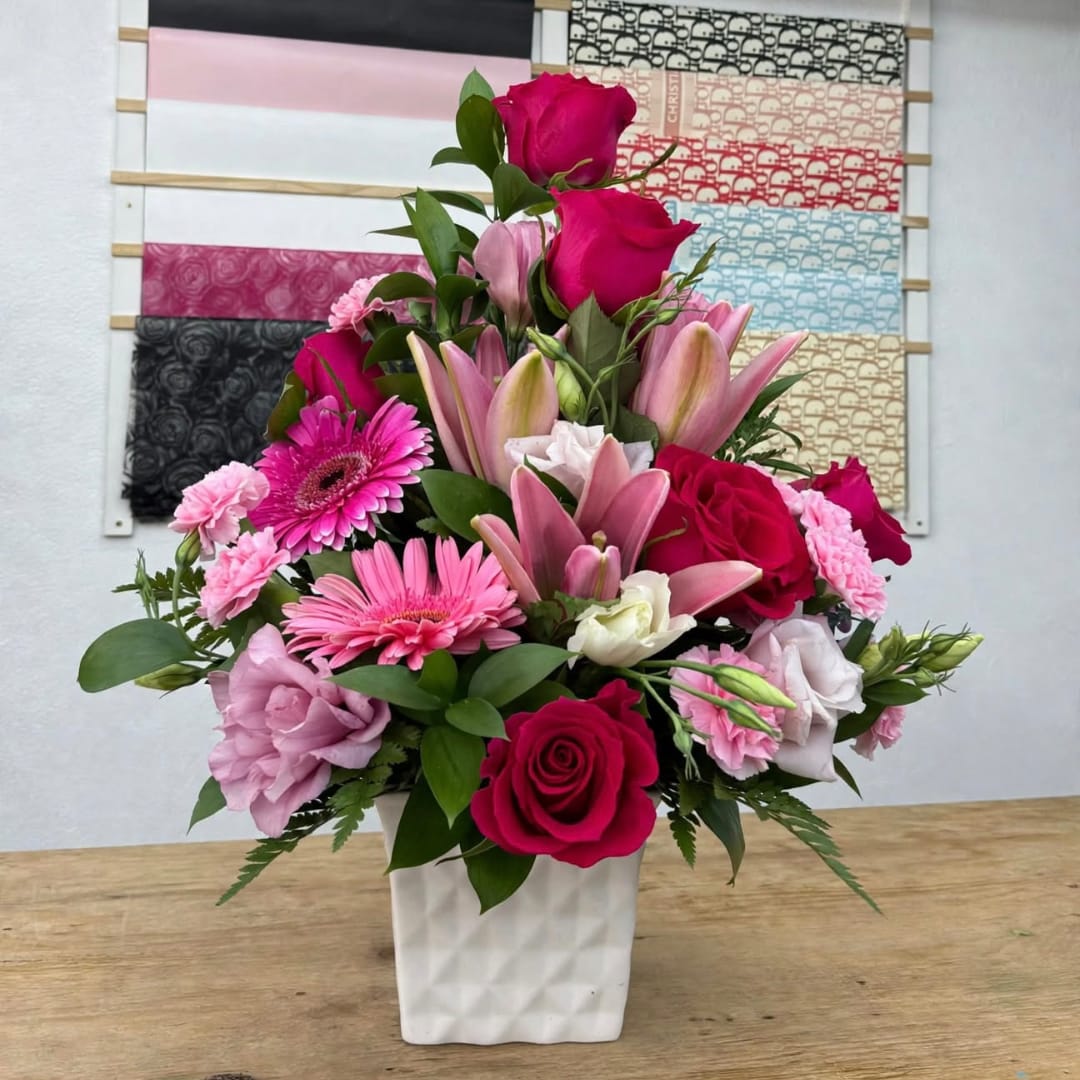 Pink and red mixed flower arrangement in a white vase