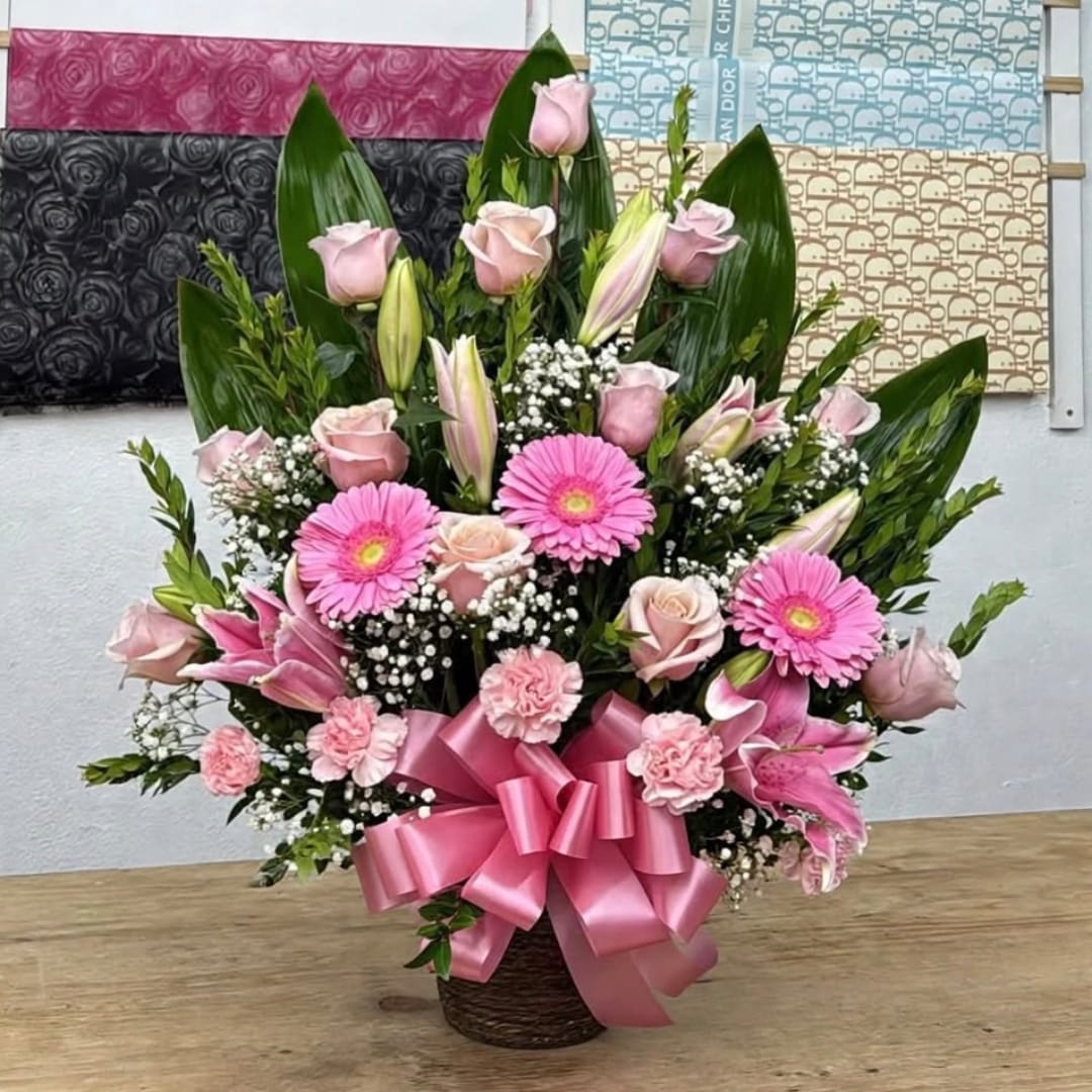 Pink floral arrangement in a basket with a large ribbon