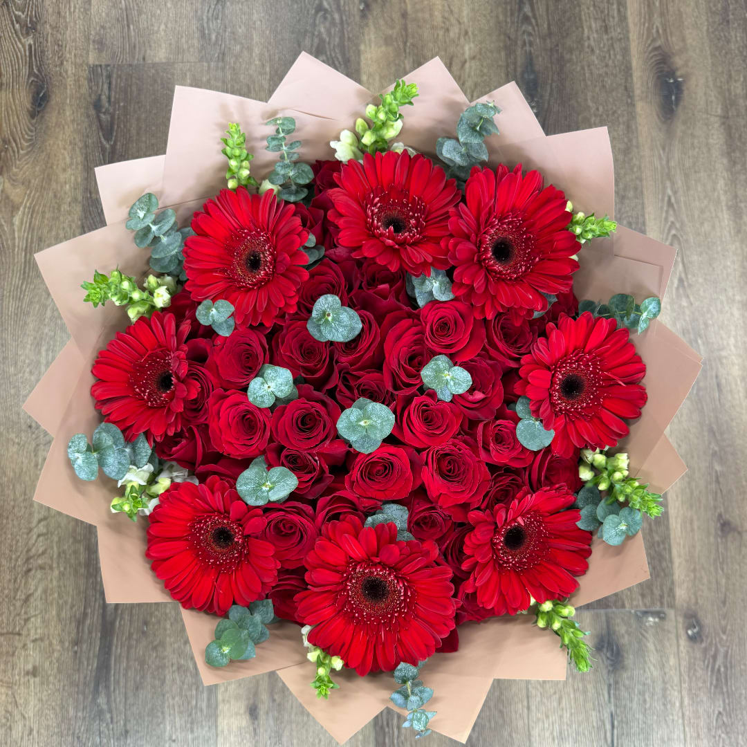 Bouquet of red roses and red gerbera daisies with pale wrapping