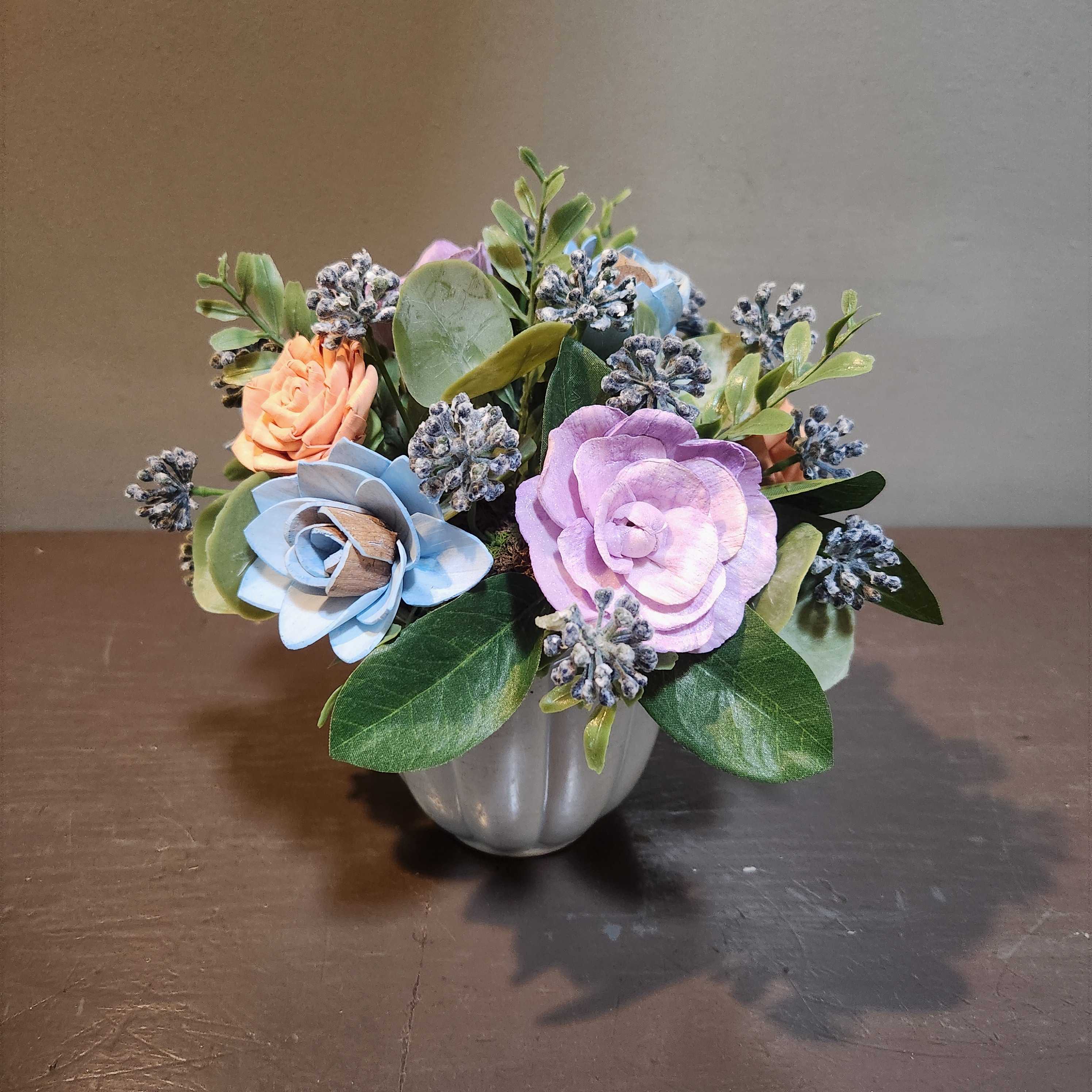 Small pastel floral arrangement in a silver vase with blue and lavender blooms