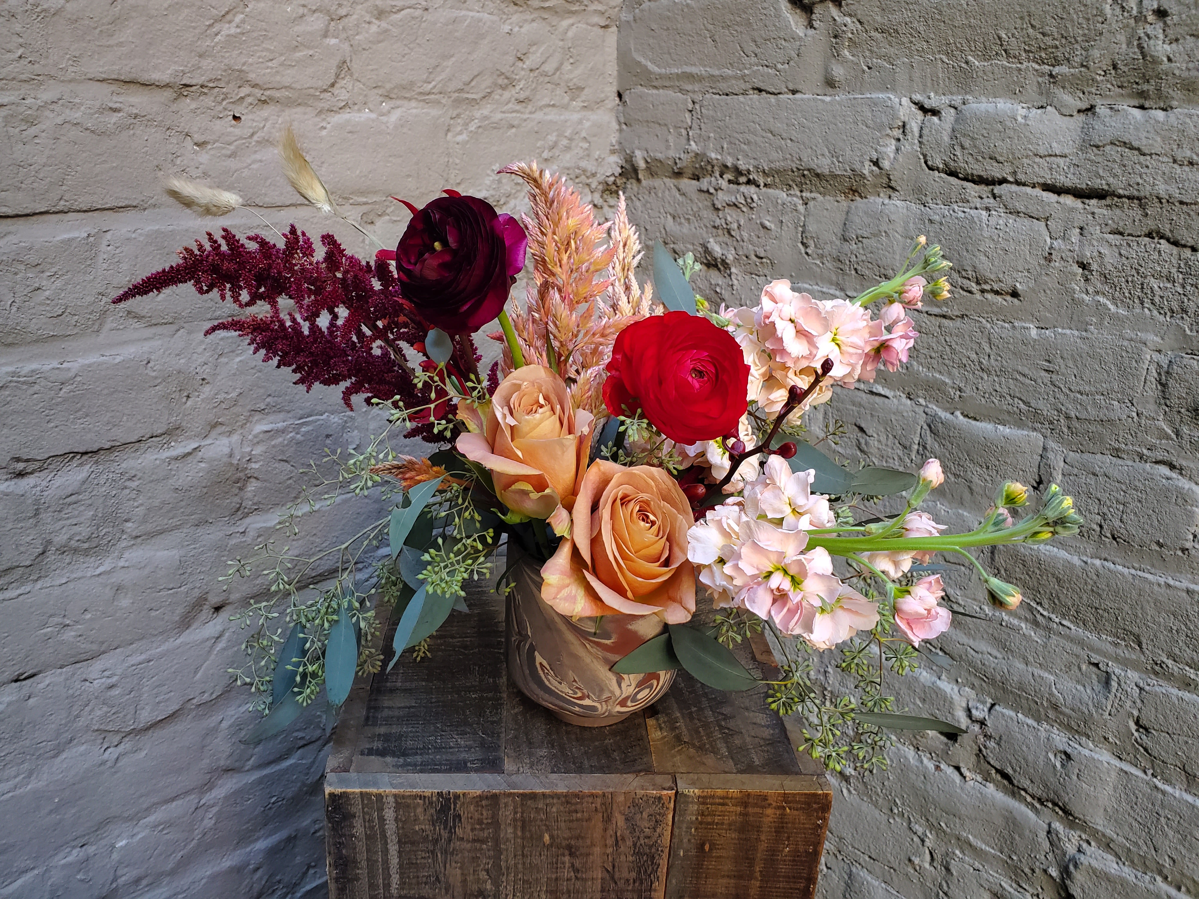 Mixed bouquet of roses and pale pink blooms in a ceramic vase