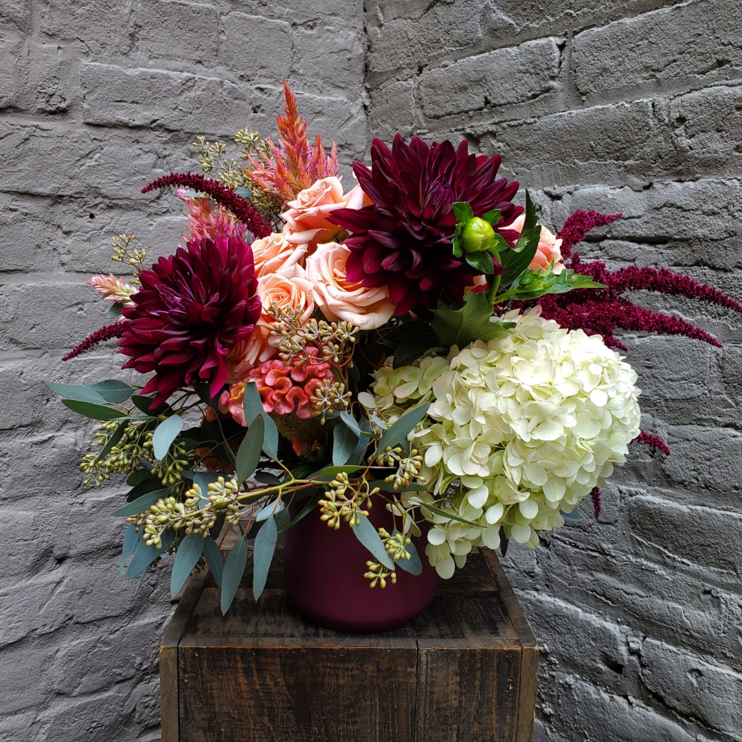 Bouquet of burgundy dahlias, blush roses, and white hydrangea in a vase