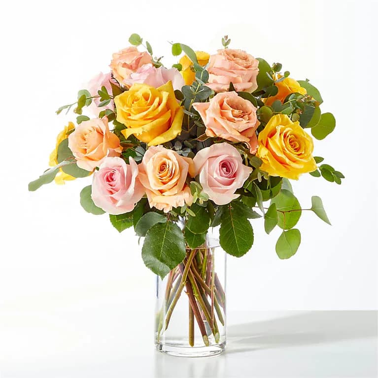 Bouquet of pink and yellow roses in a clear glass vase