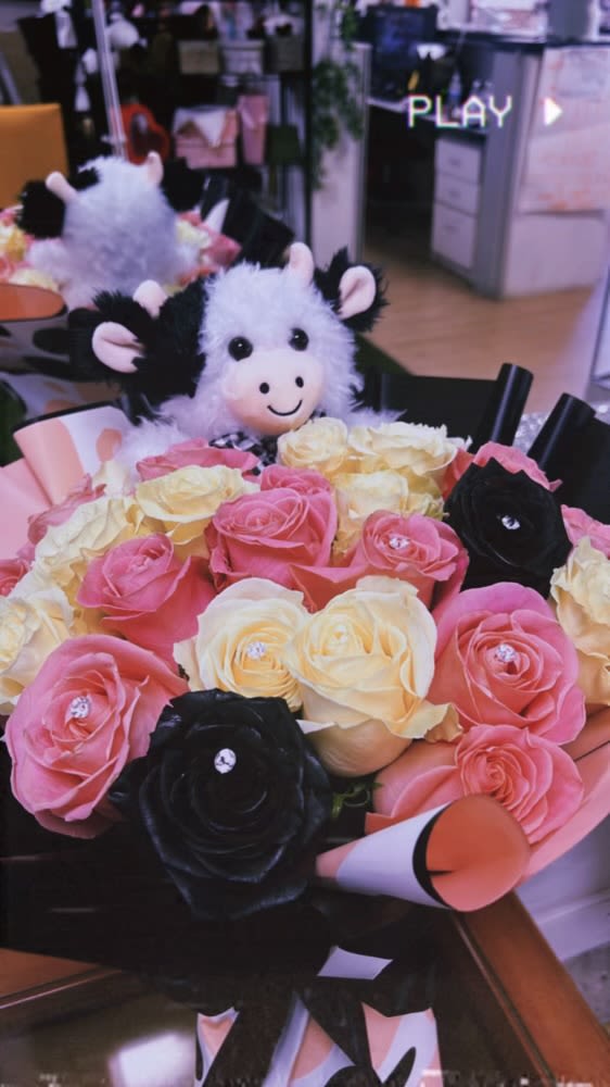 Bouquet of pink, cream, and black roses with a plush cow toy