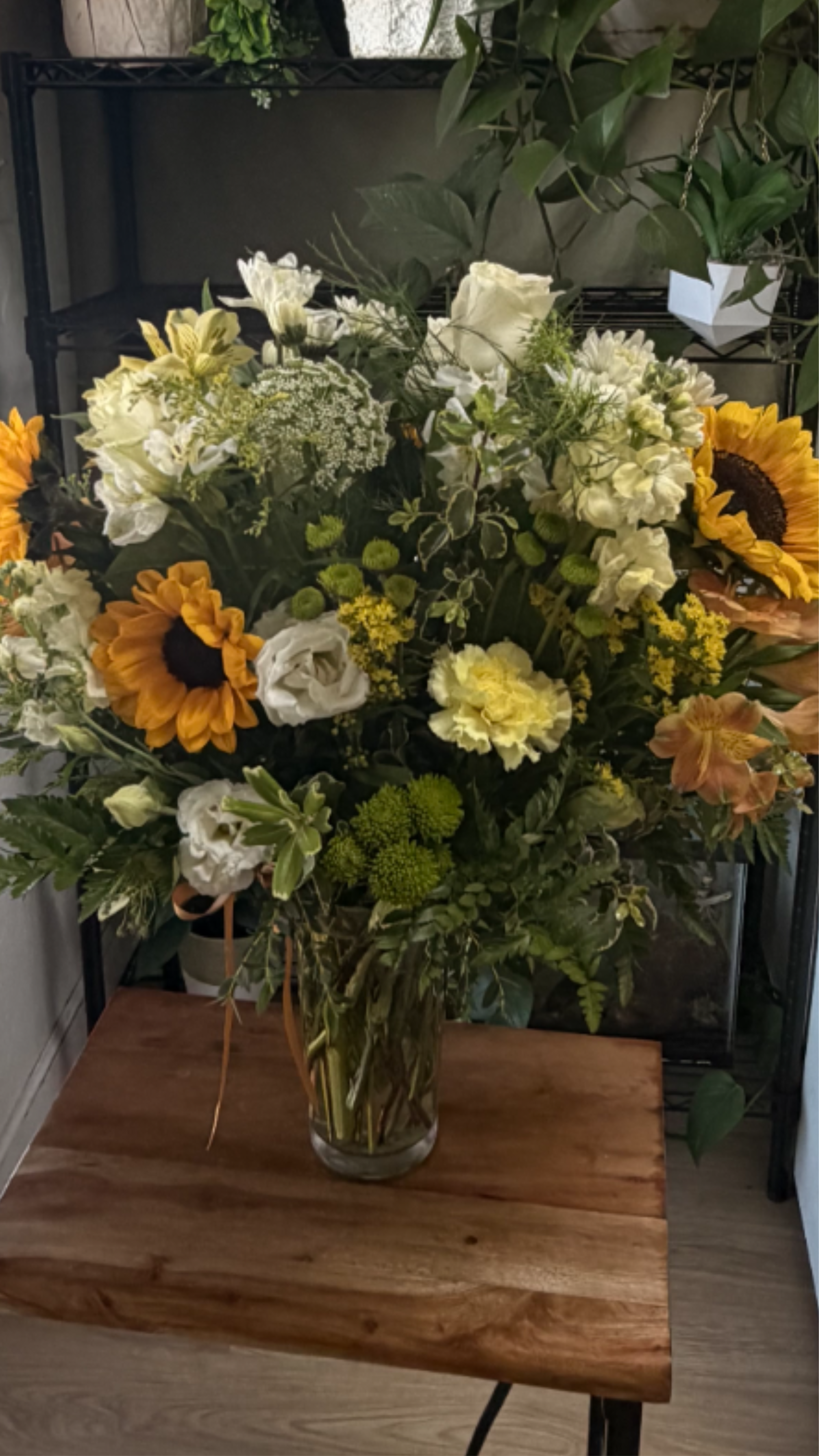 Large mixed bouquet in a clear glass vase with sunflowers and white blooms