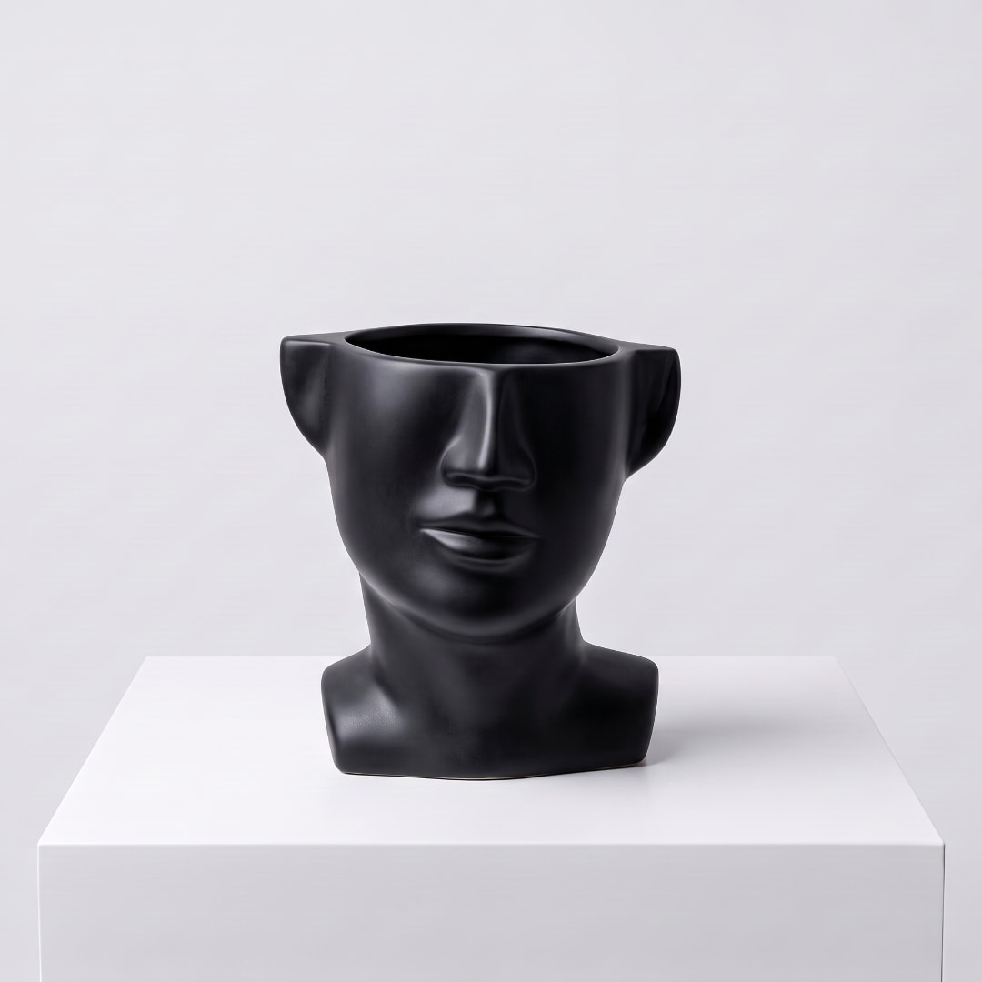 Black face-shaped vase on a white pedestal
