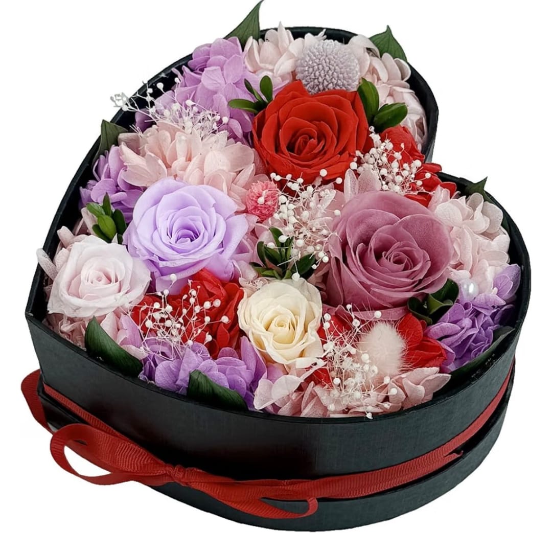 Heart-shaped box of pastel and red roses with a ribbon bow