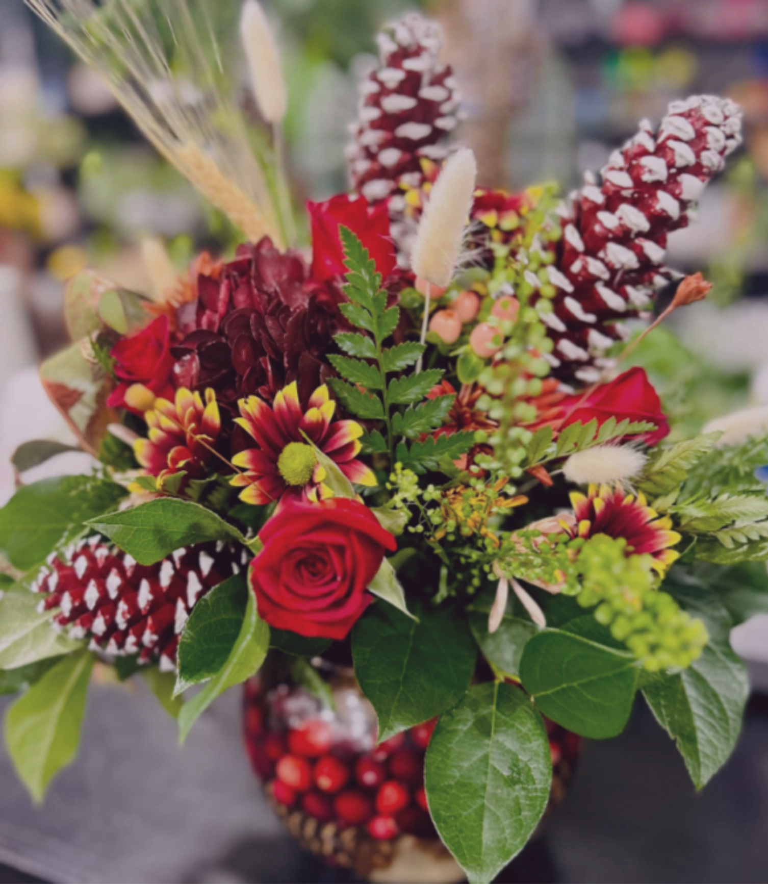 Fall Bubble - A fall centerpiece featuring pine cones and cranberries arranged in a bubble bowl, combined with autumn florals and wheat.