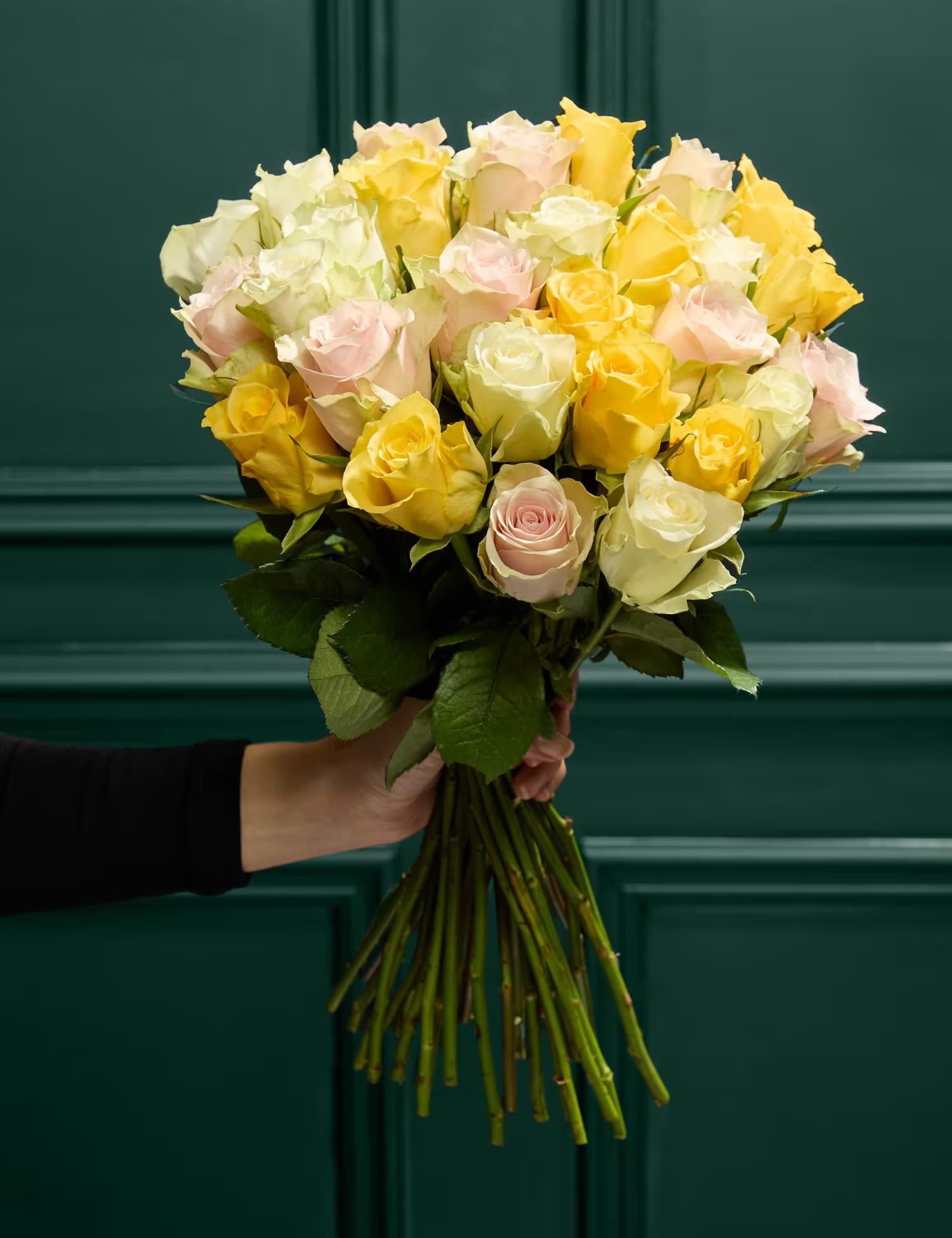 Handheld bouquet of pale yellow, cream, and blush roses