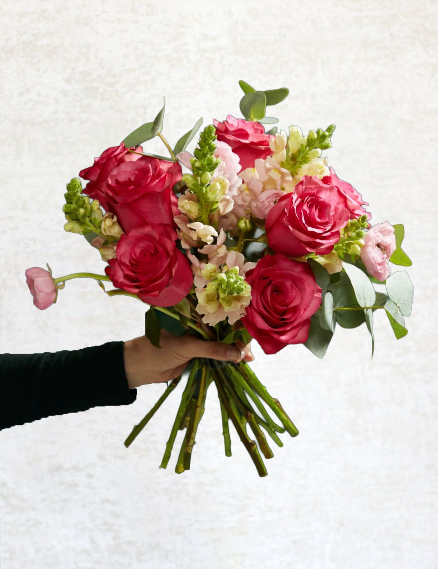 Handheld bouquet of pink roses and pale snapdragons