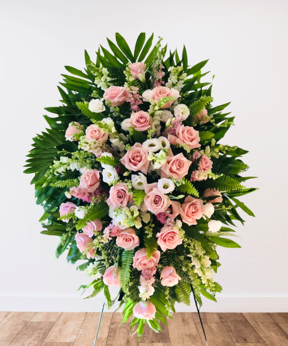 Large standing spray of pink roses and white flowers with tropical greenery