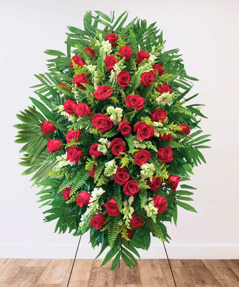 Standing spray of red roses with white accents and tropical greenery