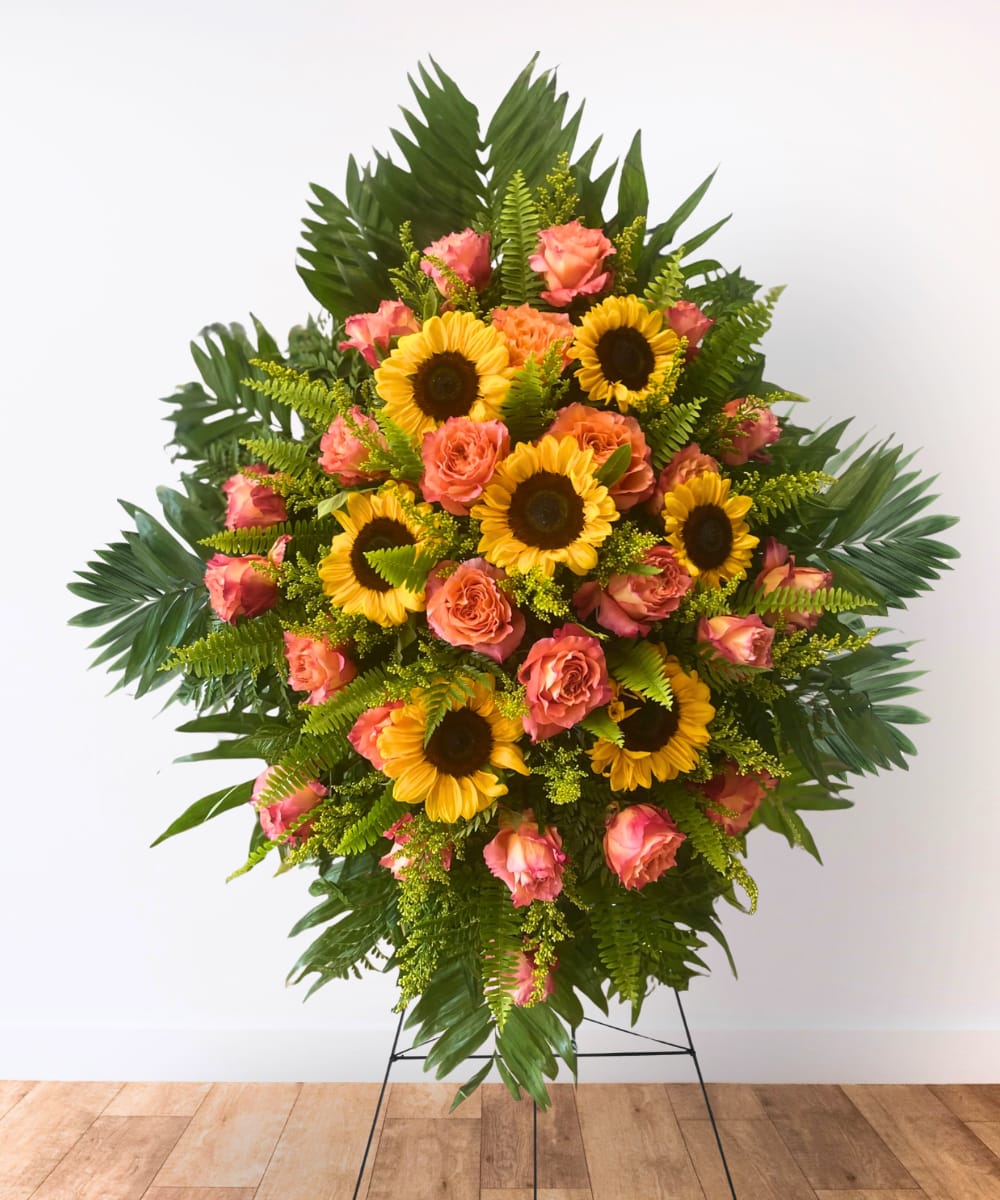 Standing floral spray with sunflowers and pink roses on a metal easel