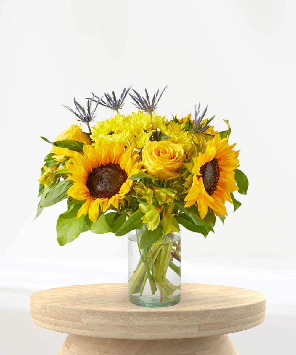 Sunflower and yellow rose bouquet in a clear glass vase